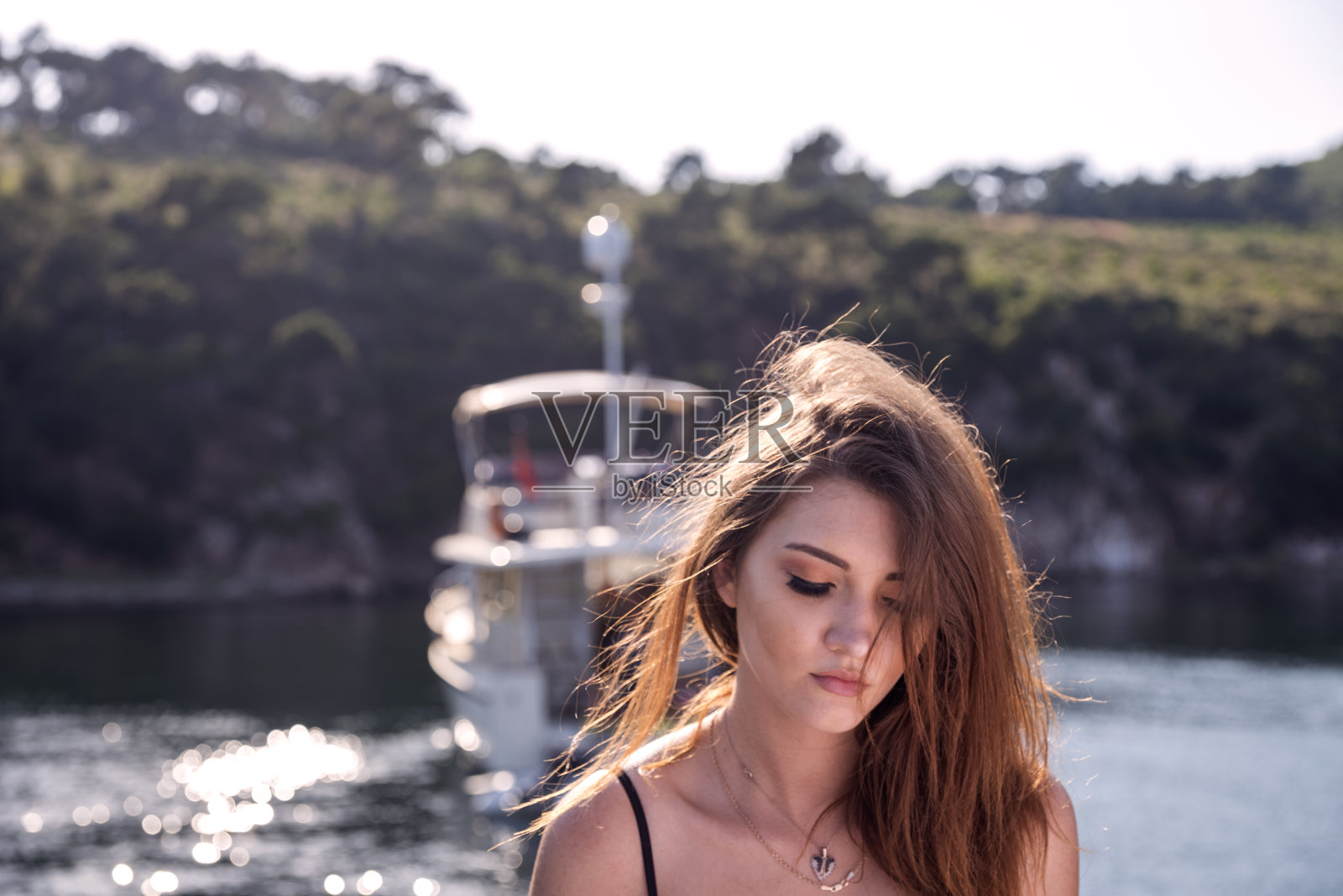 年轻的乌克兰女模特坐在游艇与泳装附近的海岸，土耳其伊斯坦布尔照片摄影图片