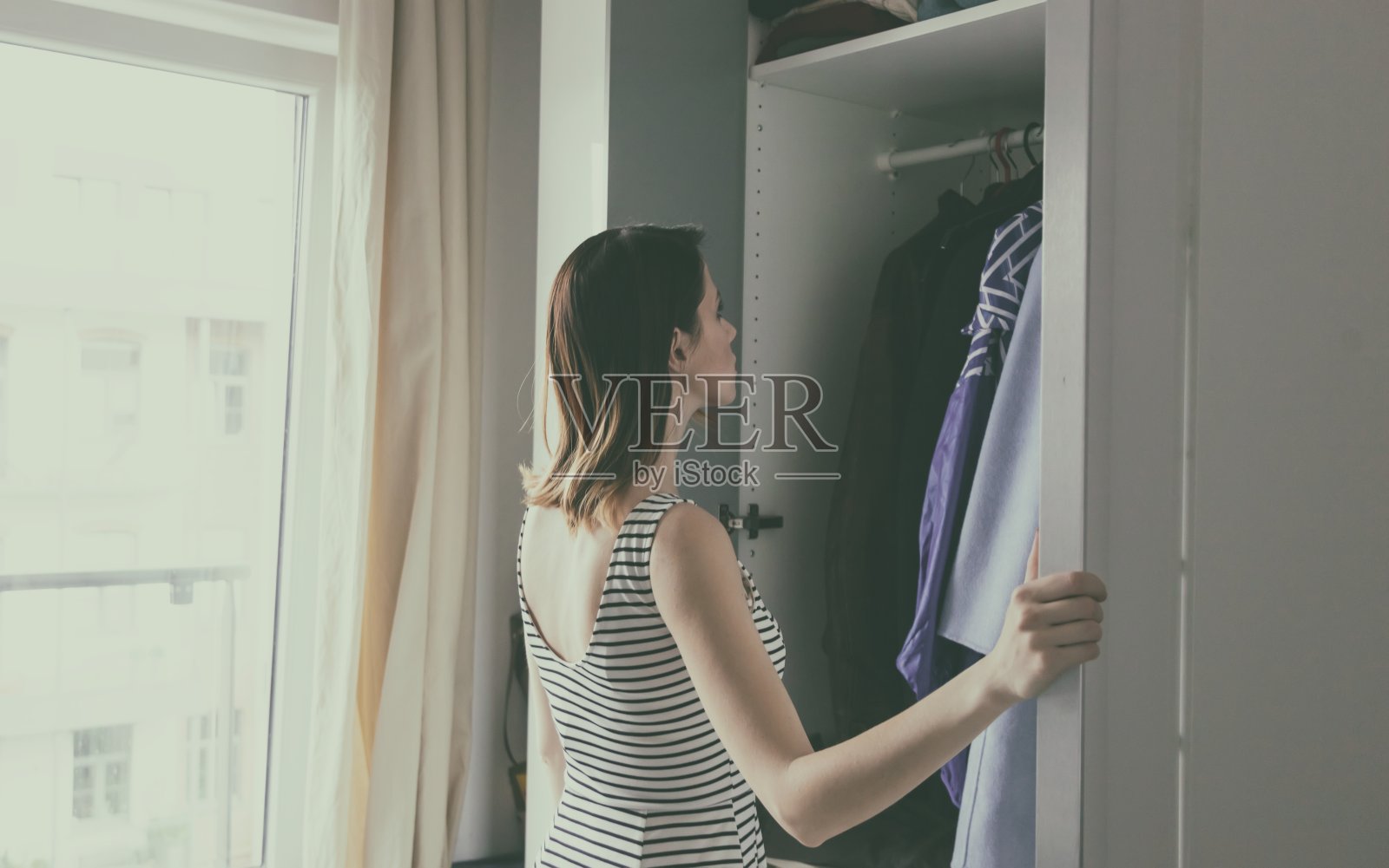 年轻的红头发女孩正在挑选衣服照片摄影图片