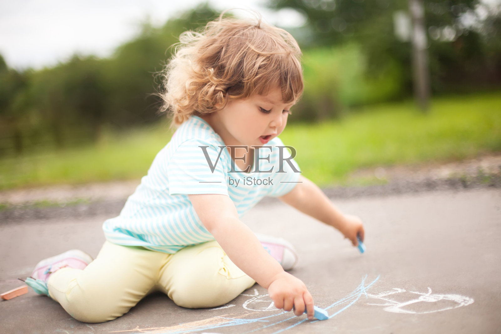 可爱的学步小女孩用一块彩色粉笔画画照片摄影图片