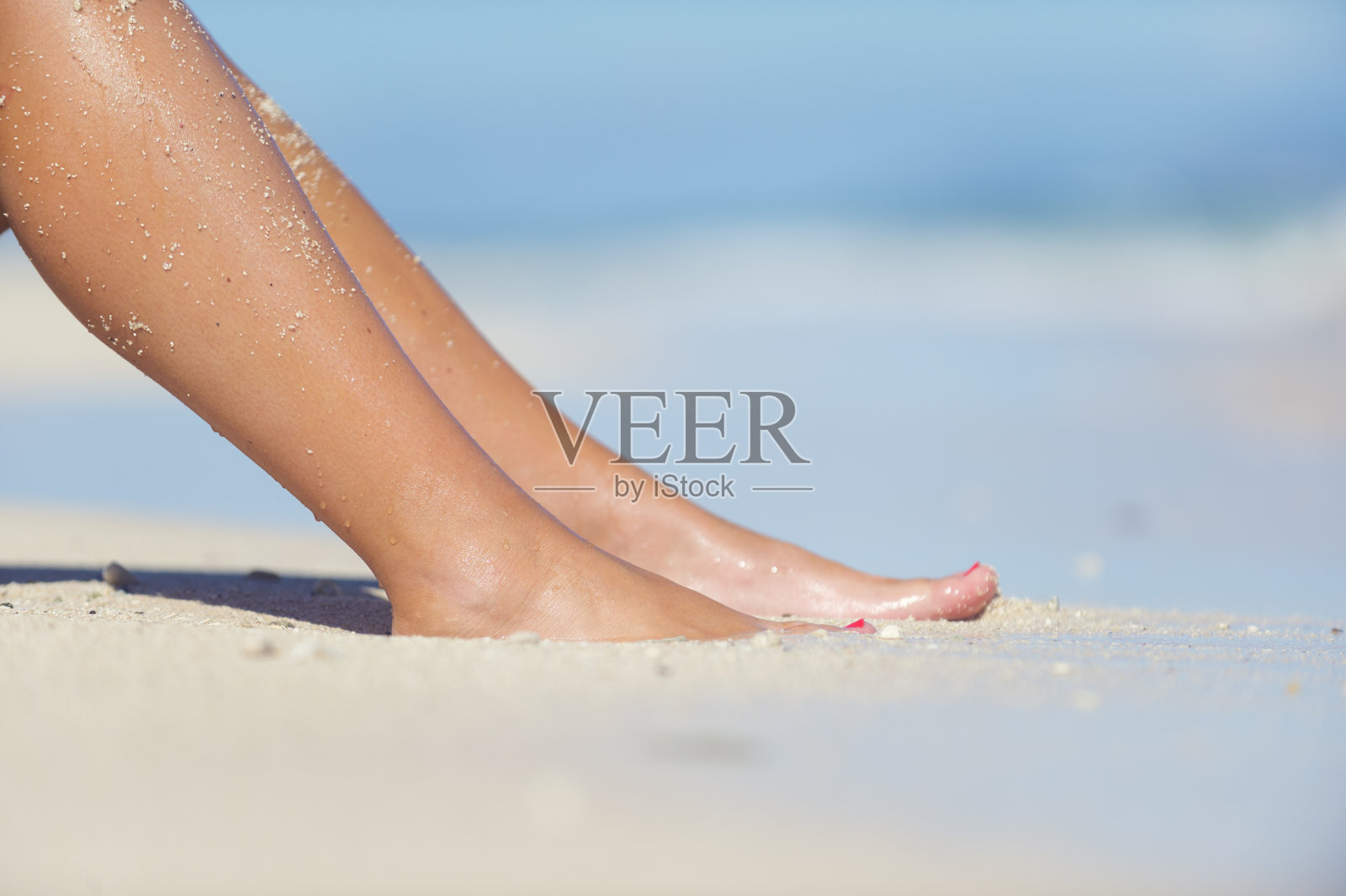 女人的腿独自在海滩上。照片摄影图片