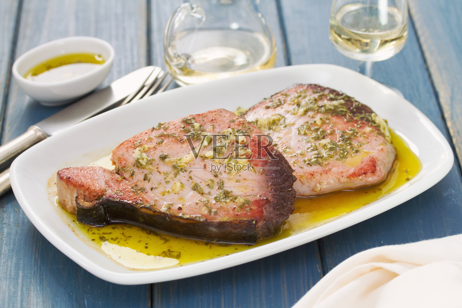 配酱汁的金枪鱼，白色的盘子，蓝色的木头背景照片摄影图片