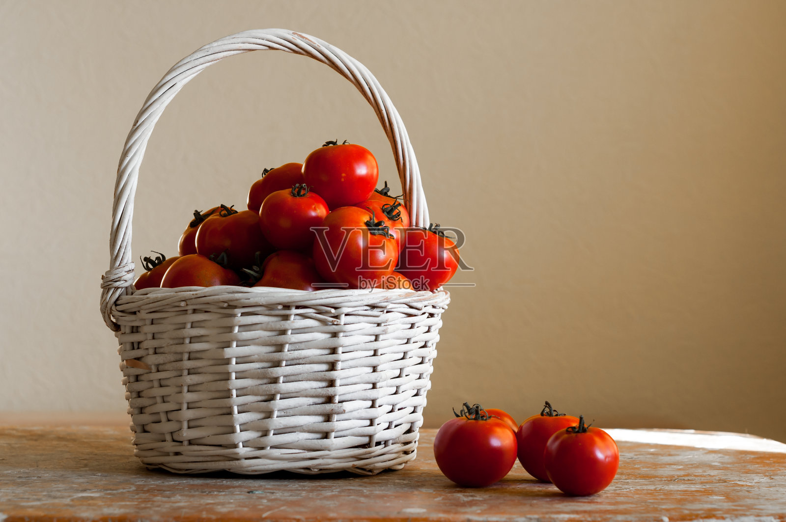 白色的木桌上，编织的篮子里装着红色的樱桃番茄照片摄影图片
