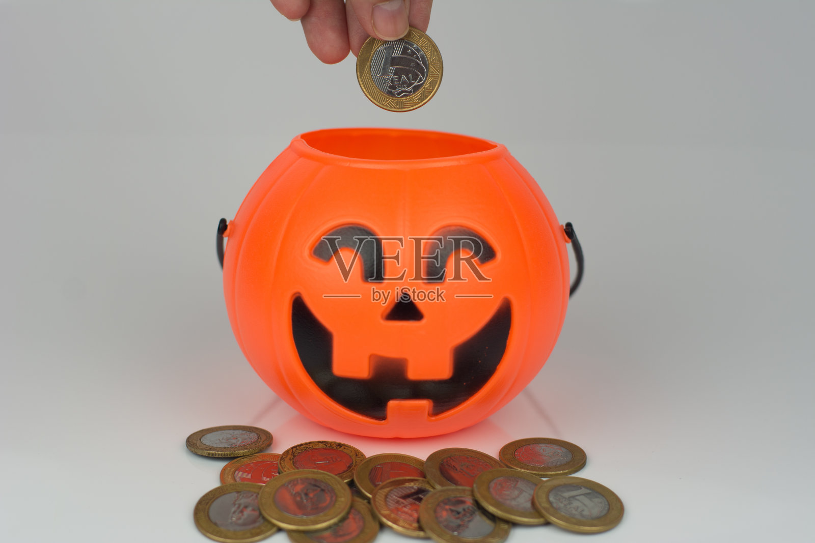 手把一枚硬币放进万圣节南瓜里照片摄影图片