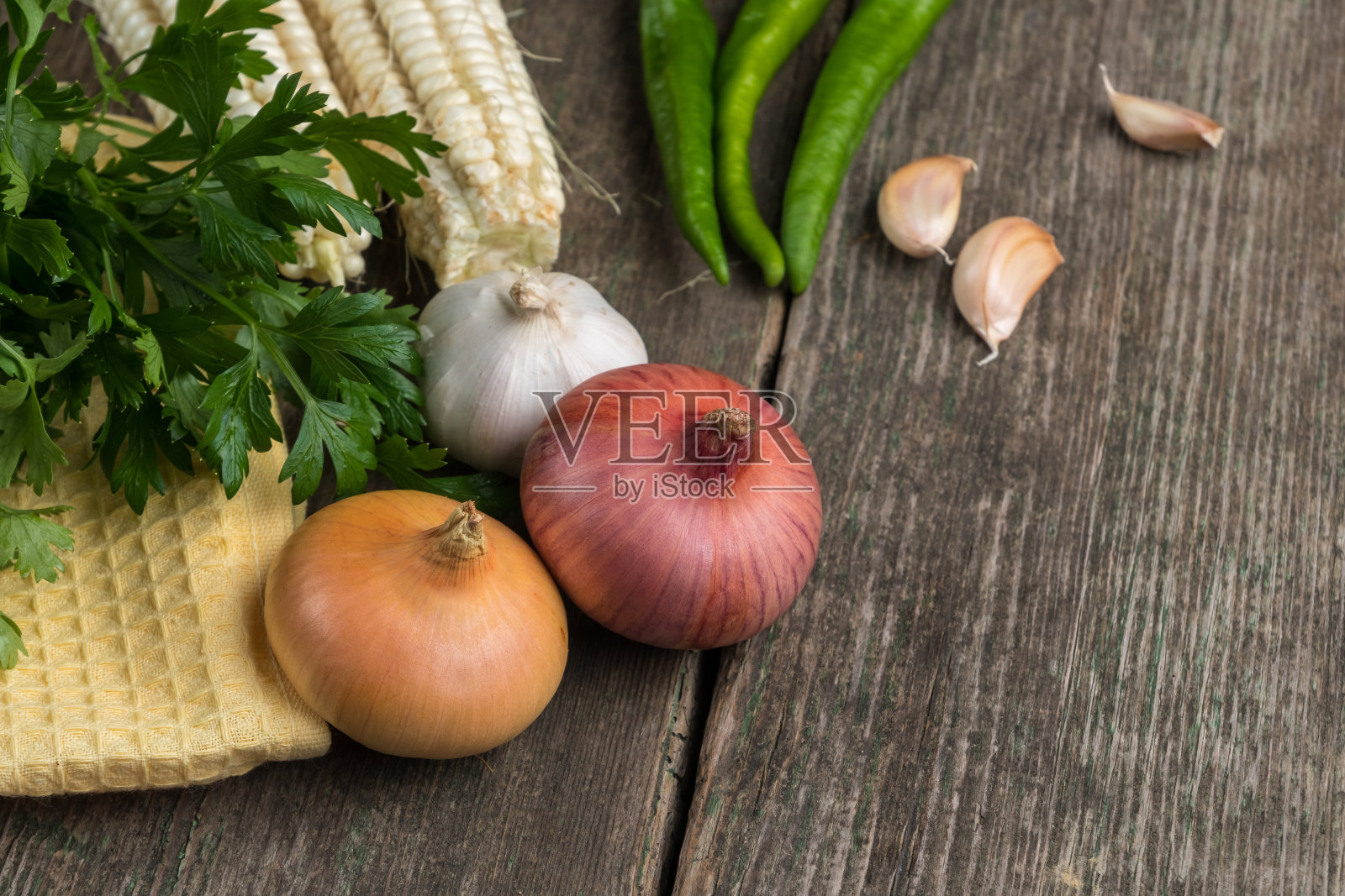 洋葱，玉米，大蒜，胡椒，香菜和欧芹放在一块旧木板上照片摄影图片
