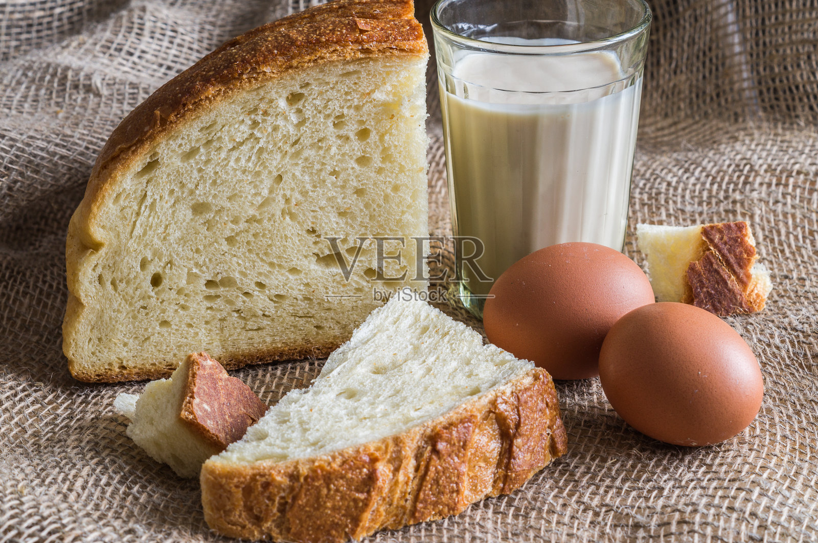 自制面包，鸡蛋，牛奶，放在一个旧的粗麻袋上，乡村风格。照片摄影图片