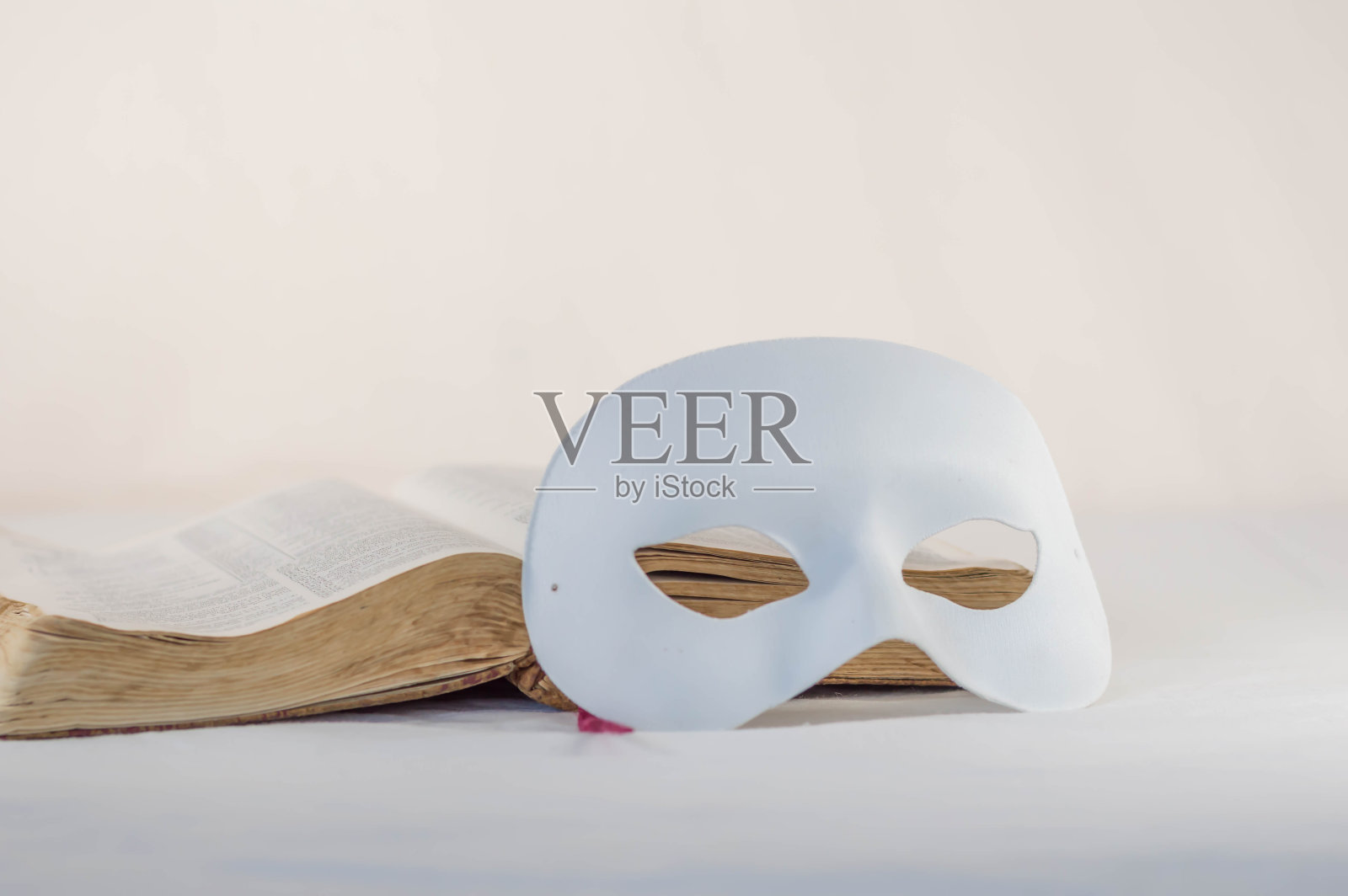 在一本旧圣经前戴面具照片摄影图片