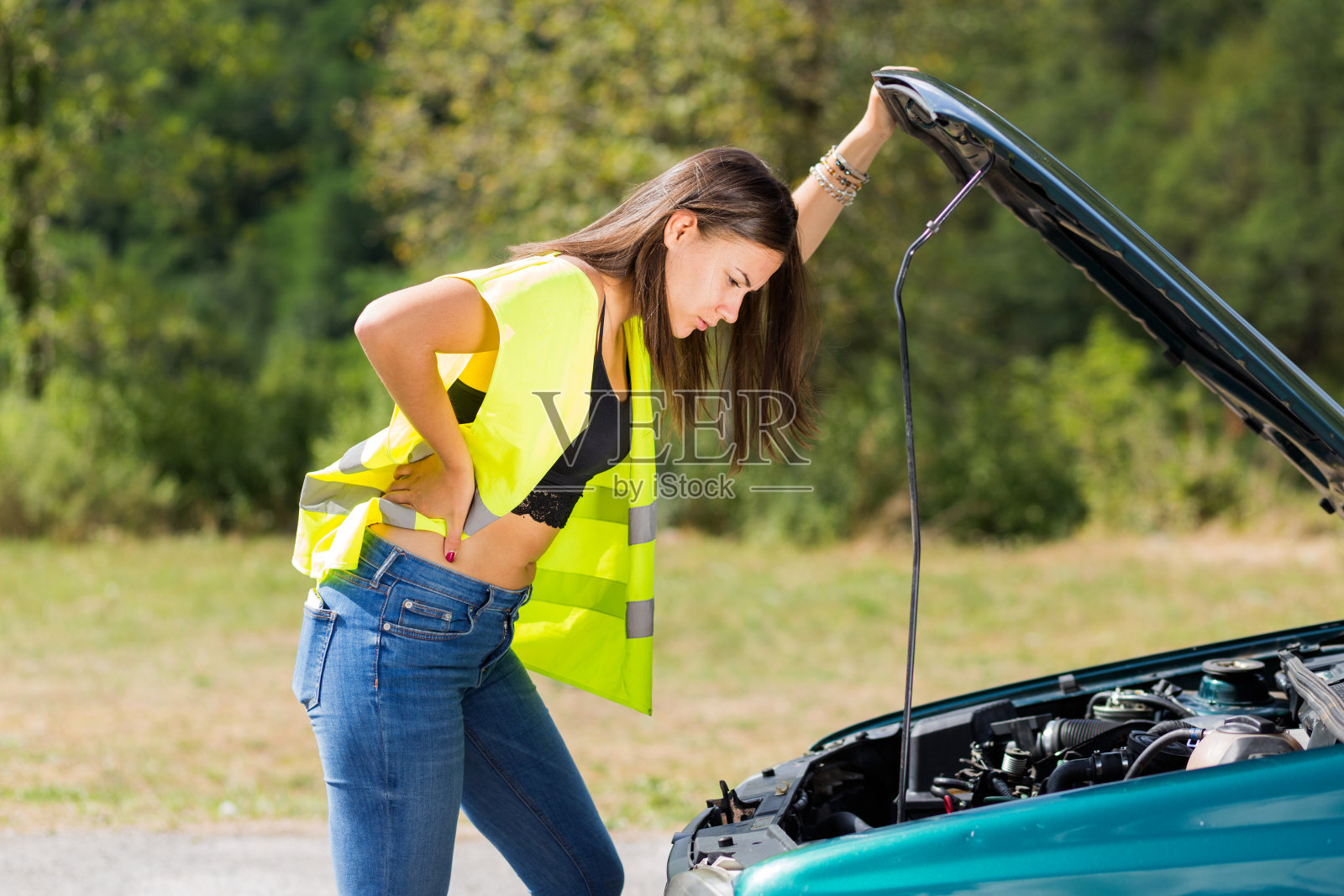 白人女性白人模特看她的汽车引擎盖下面照片摄影图片