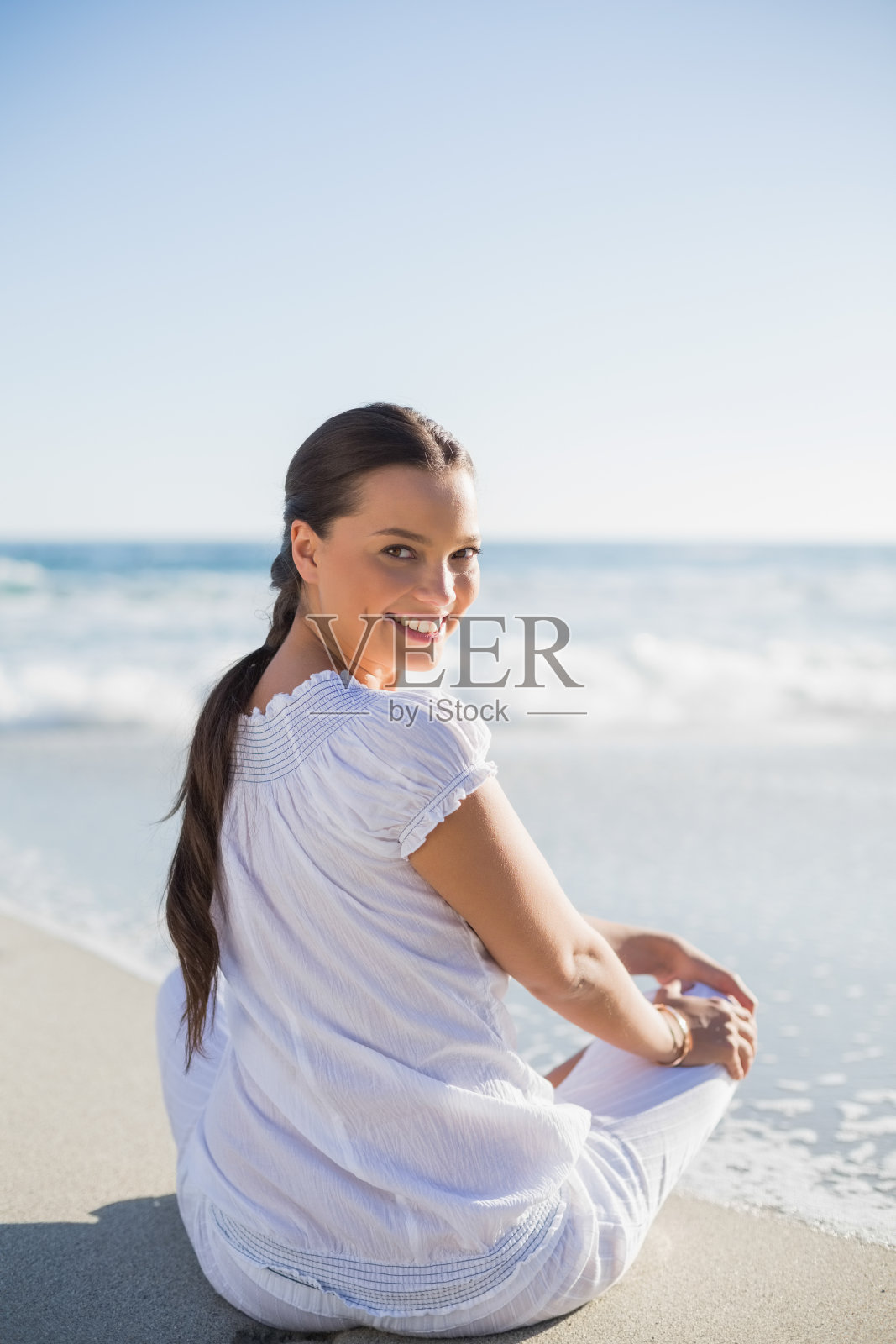 微笑的女人在海滩上向后看在相机的后方视图照片摄影图片