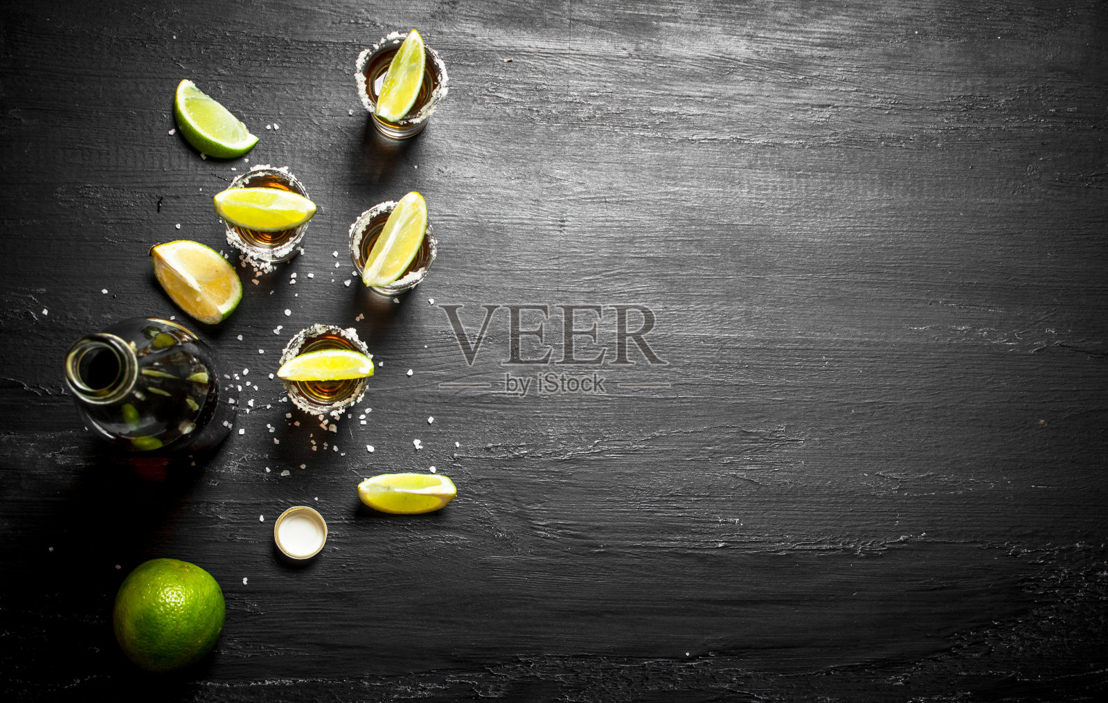 一瓶龙舌兰酒，配小酒杯，新鲜酸橙和盐。照片摄影图片