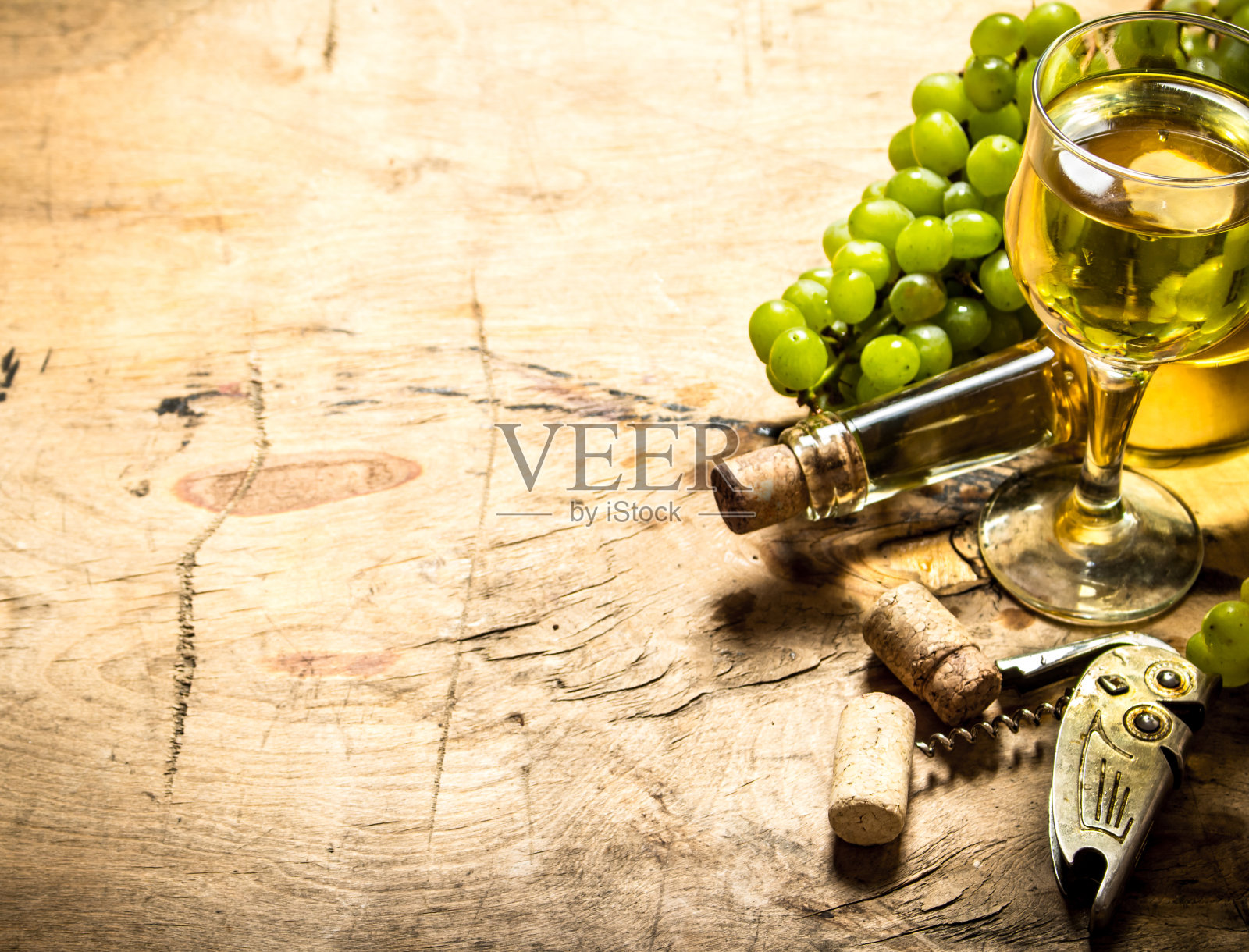 一串白葡萄配葡萄酒，一个开瓶器和瓶塞。照片摄影图片