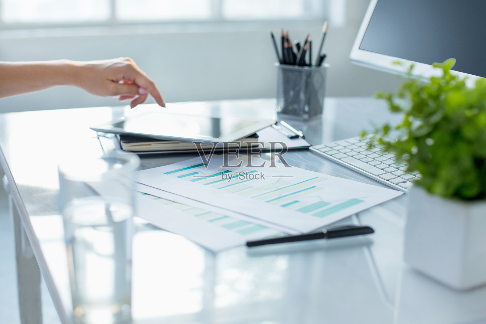 特写女性的手使用笔记本电脑，同时在现代办公室内部的电脑上工作照片摄影图片