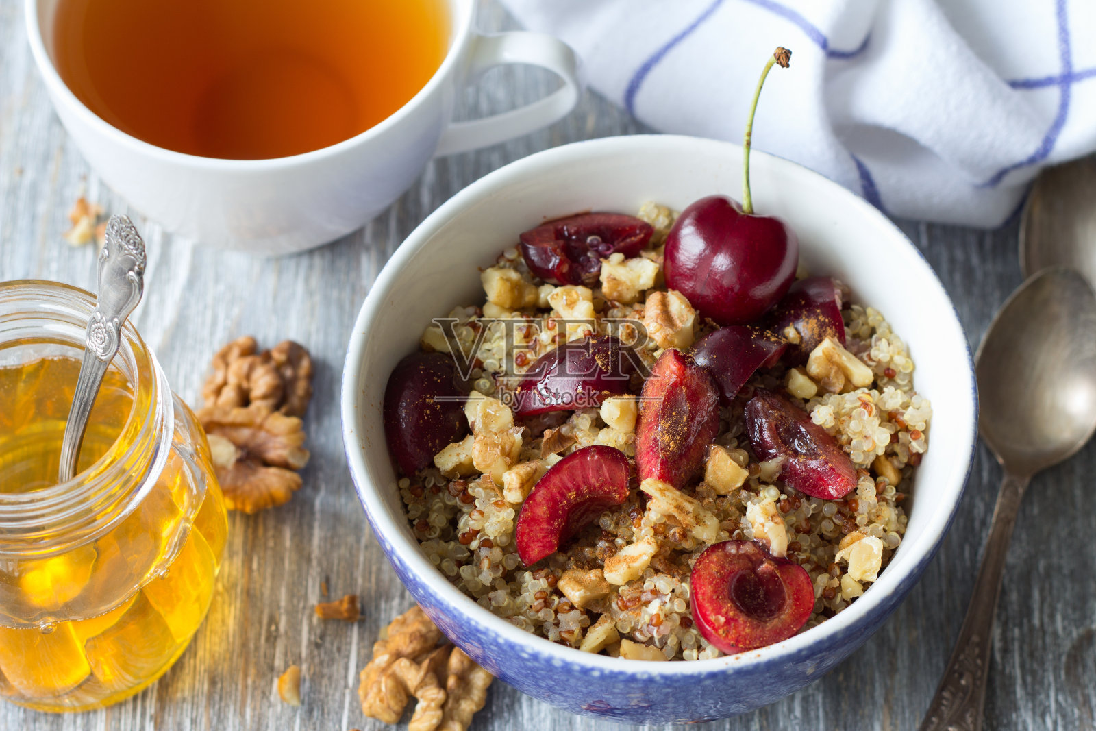 以新鲜的樱桃、核桃和蜂蜜为背景的藜麦照片摄影图片