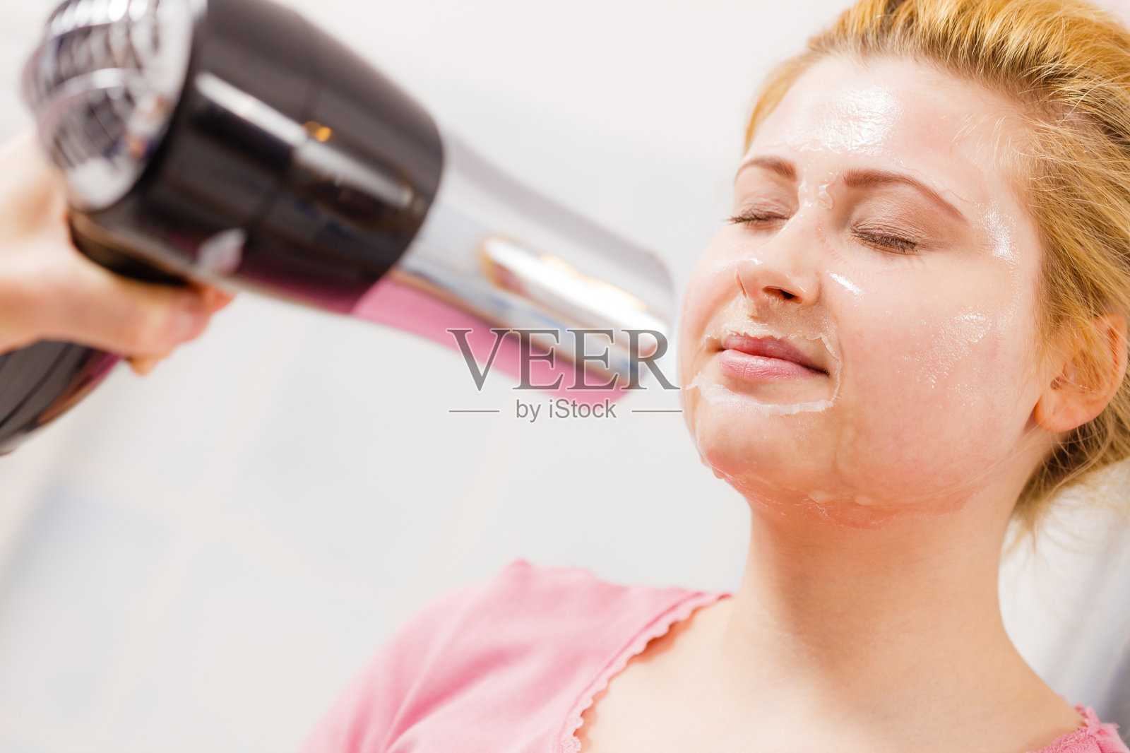 女人在吹她的剥去面膜的吹风机照片摄影图片