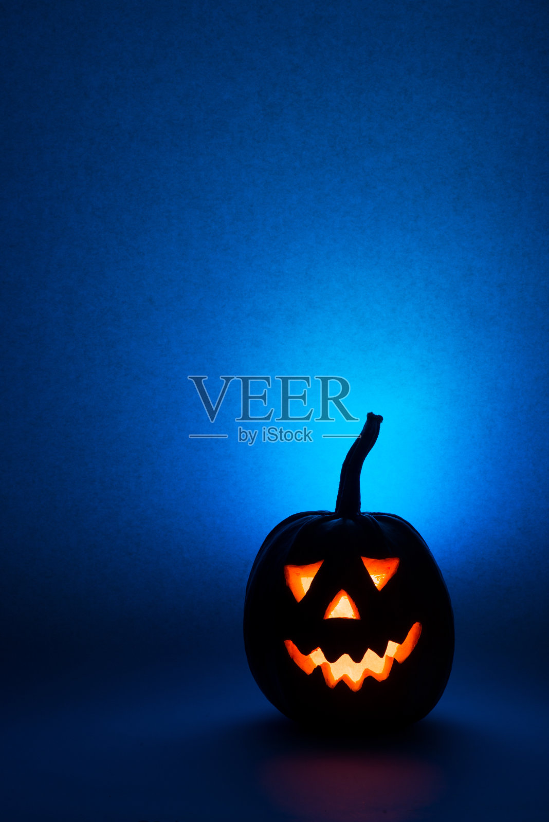 万圣节的南瓜，在蓝色的背景上滑稽的面孔剪影照片摄影图片