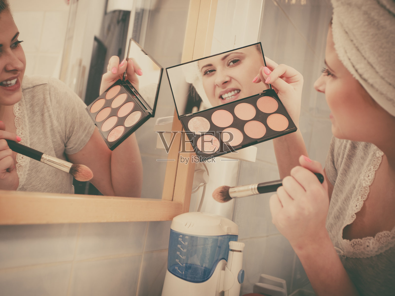 一个女人在浴室里用刷子涂古铜色照片摄影图片