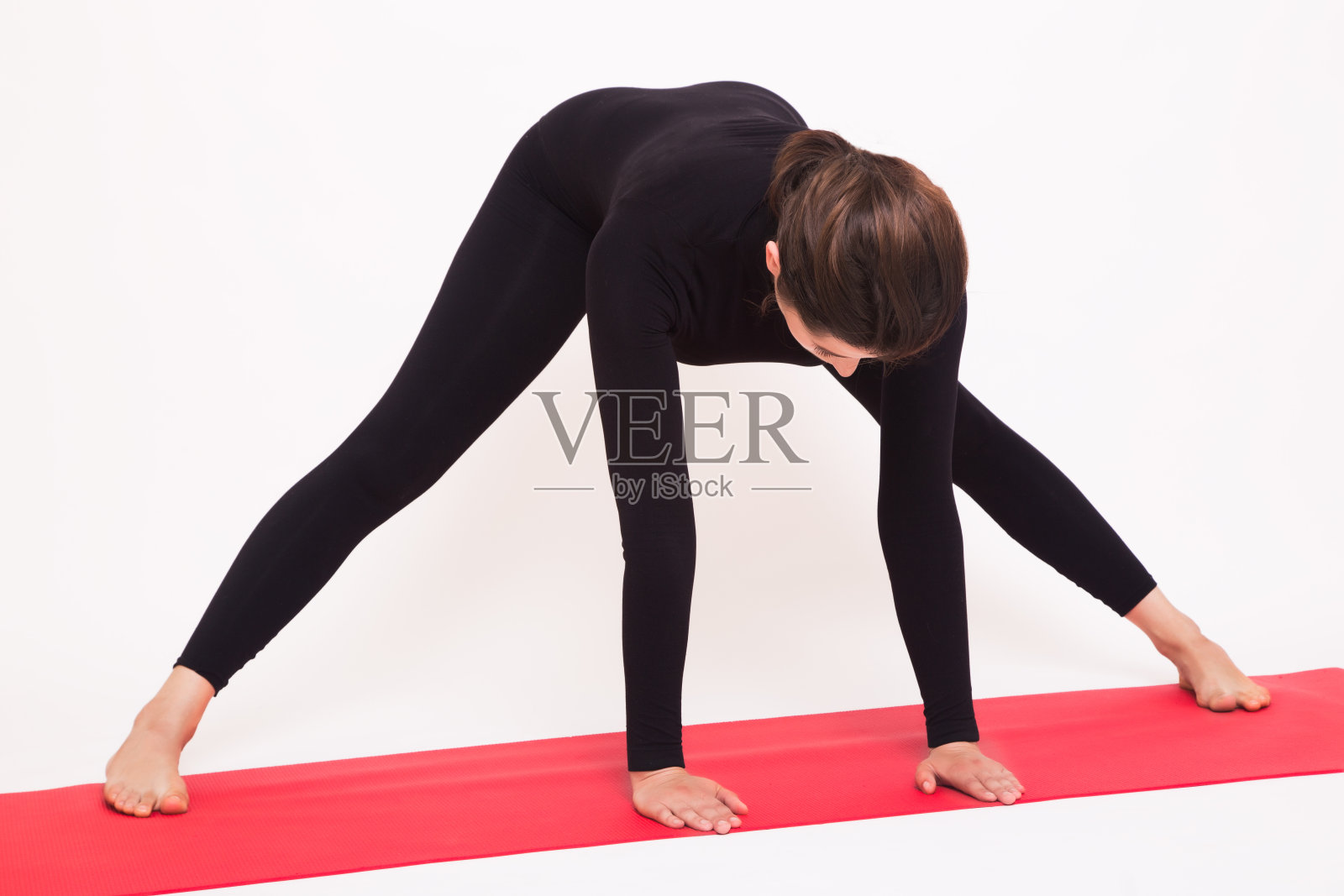 美丽的运动女孩在黑西装做瑜伽体式。孤立在白色背景上。照片摄影图片