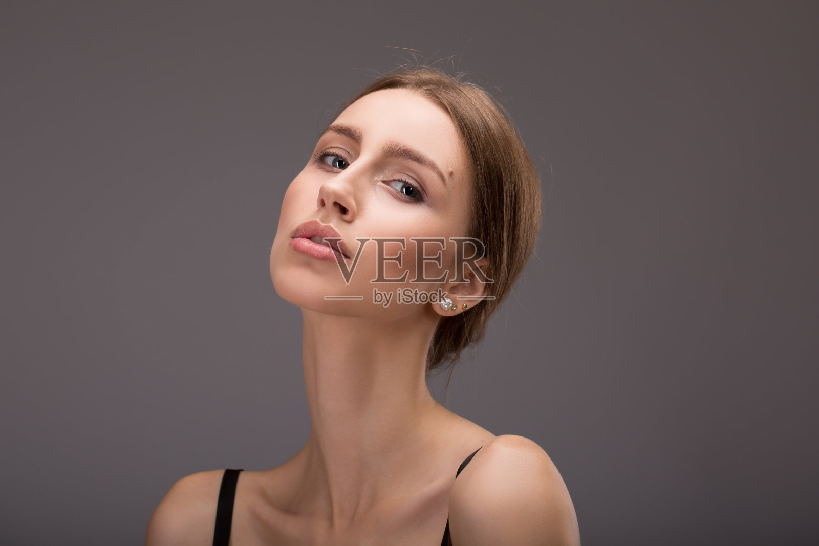 概念保健和皮肤护理。这个女人有干净整洁的皮肤和长长的棕色头发。特写肖像对浅灰色的背景。照片摄影图片