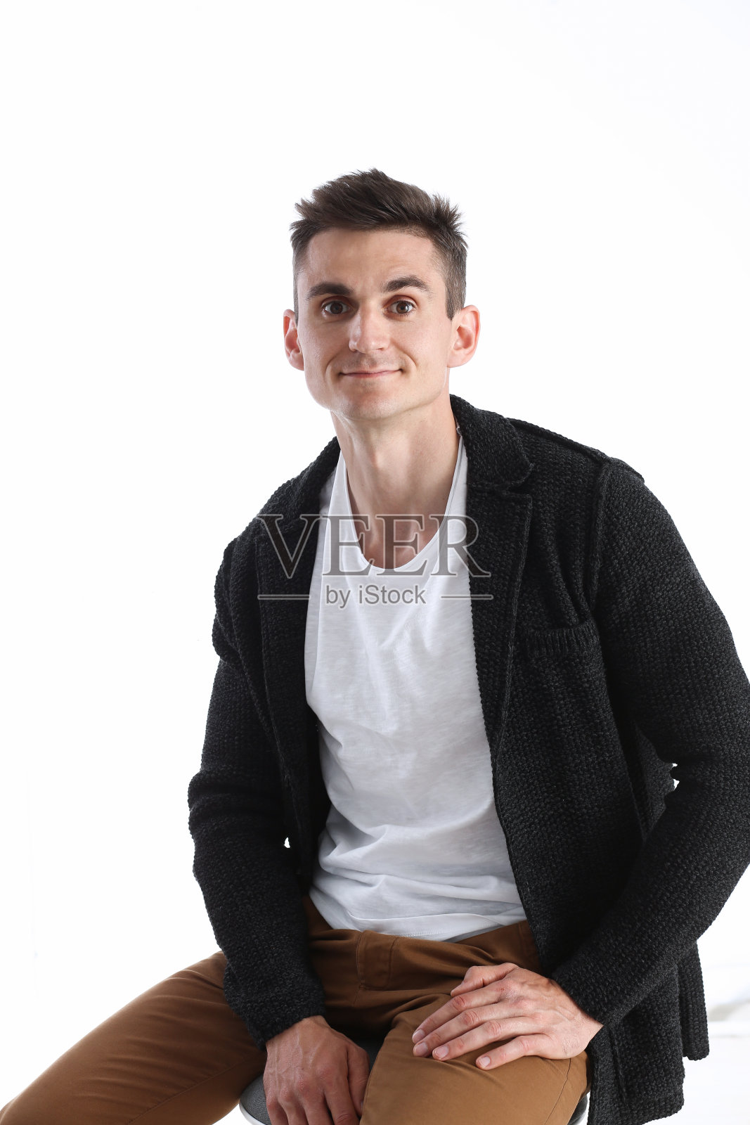 一个穿着毛衣和t恤，坐在椅子上微笑的有吸引力的男人的肖像照片摄影图片