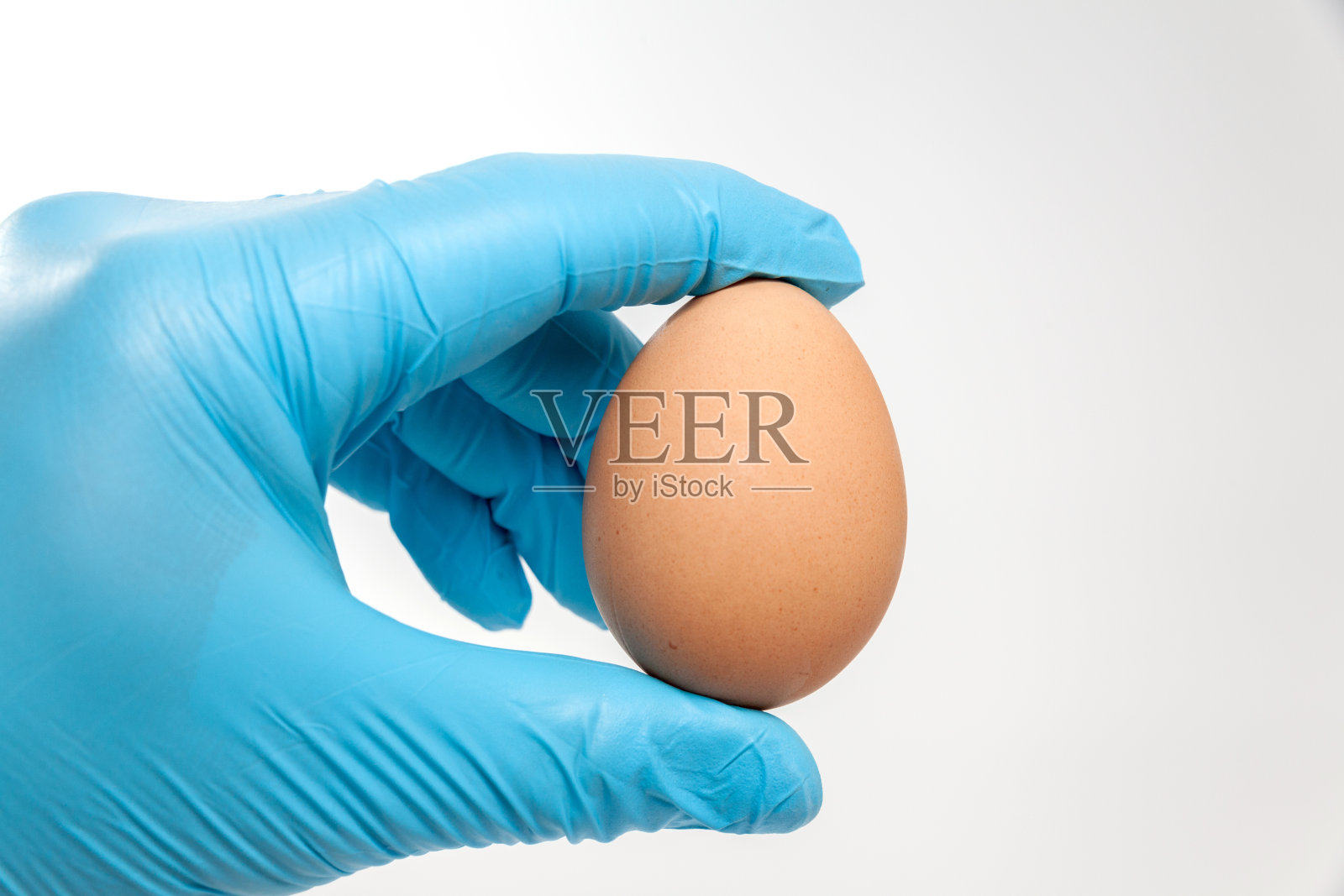 拿着鸡蛋的蓝色手套照片摄影图片