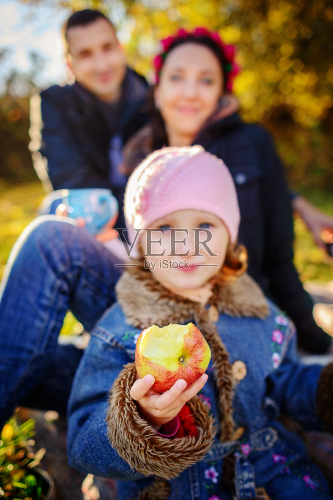 女孩坐在草地上，手里拿着一个苹果照片摄影图片