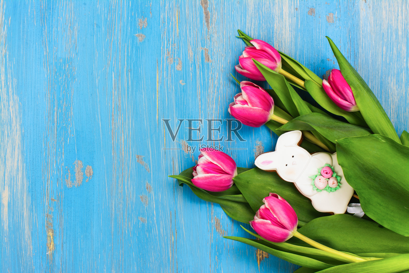 蓝色背景上的粉色郁金香和兔子饼干照片摄影图片