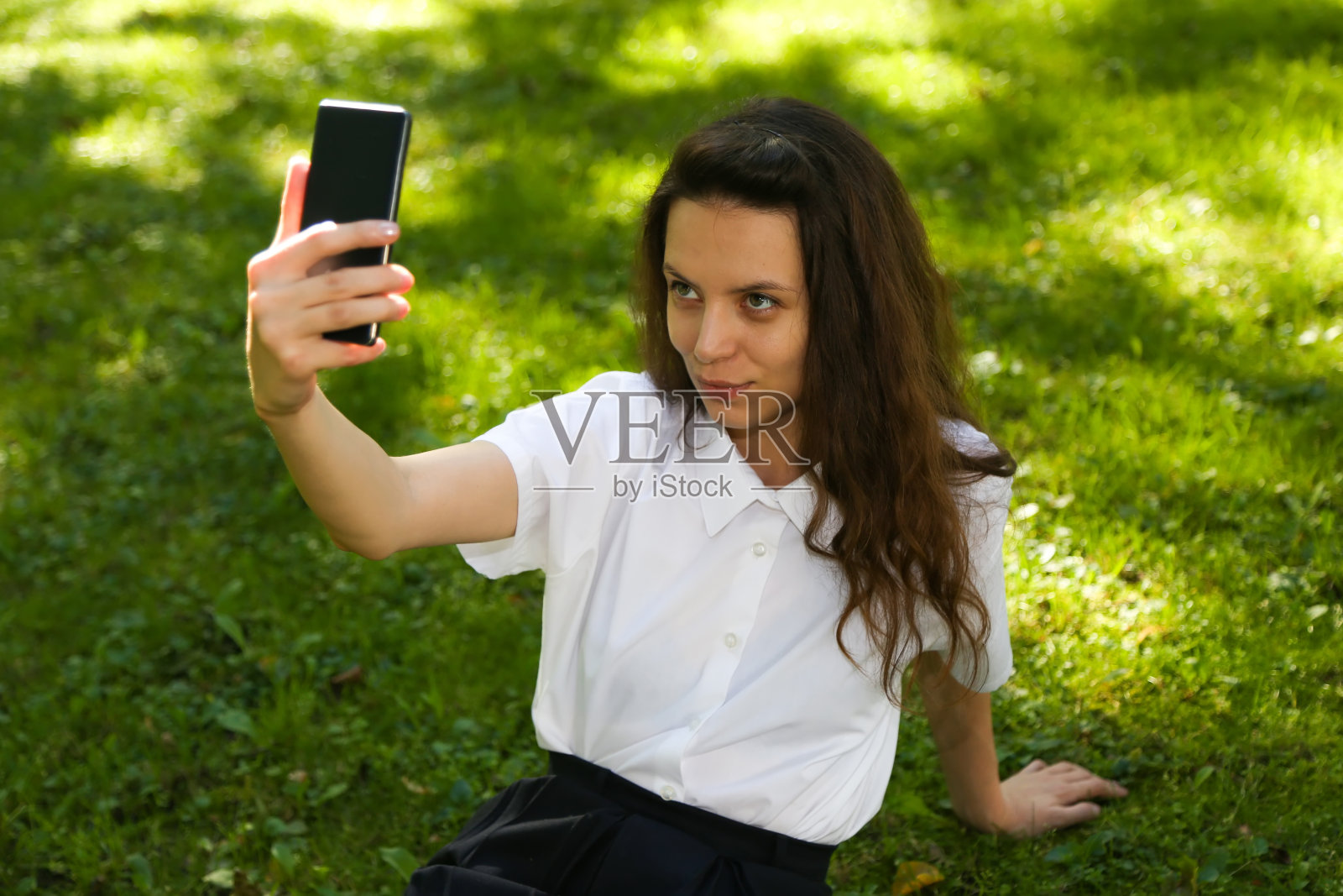 女学生坐在公园里。坐在公园的草地上看文件照片摄影图片