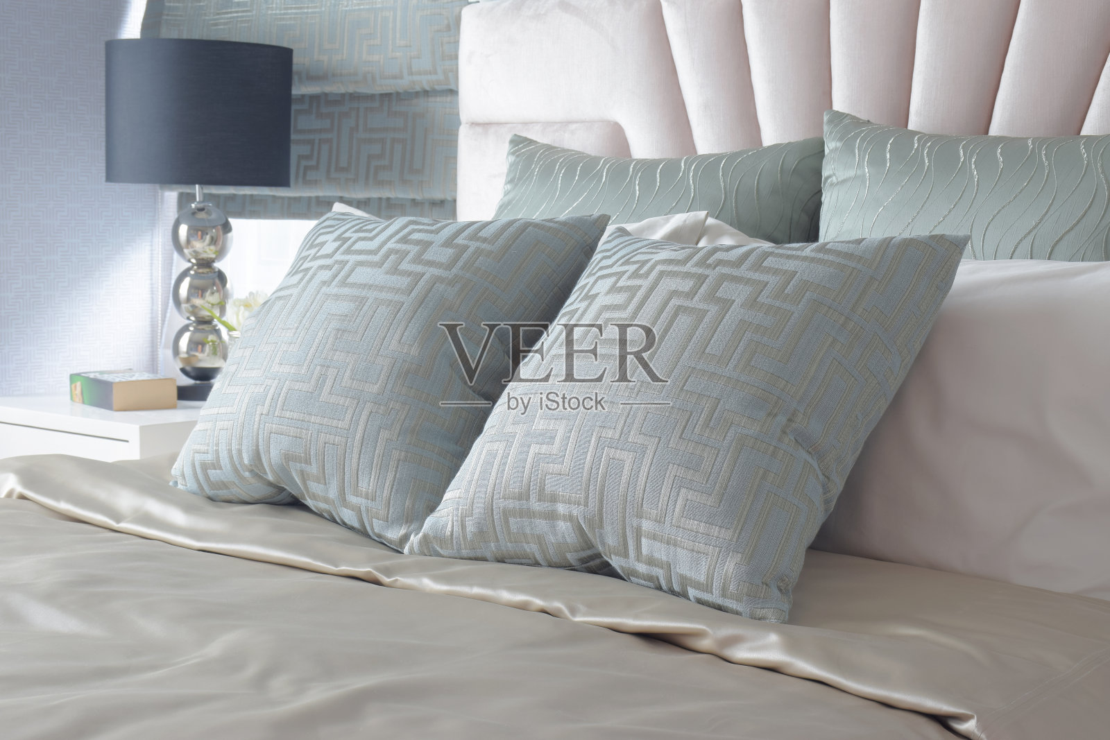 床上有浅蓝色的缎子枕头，背景是黑色的台灯照片摄影图片