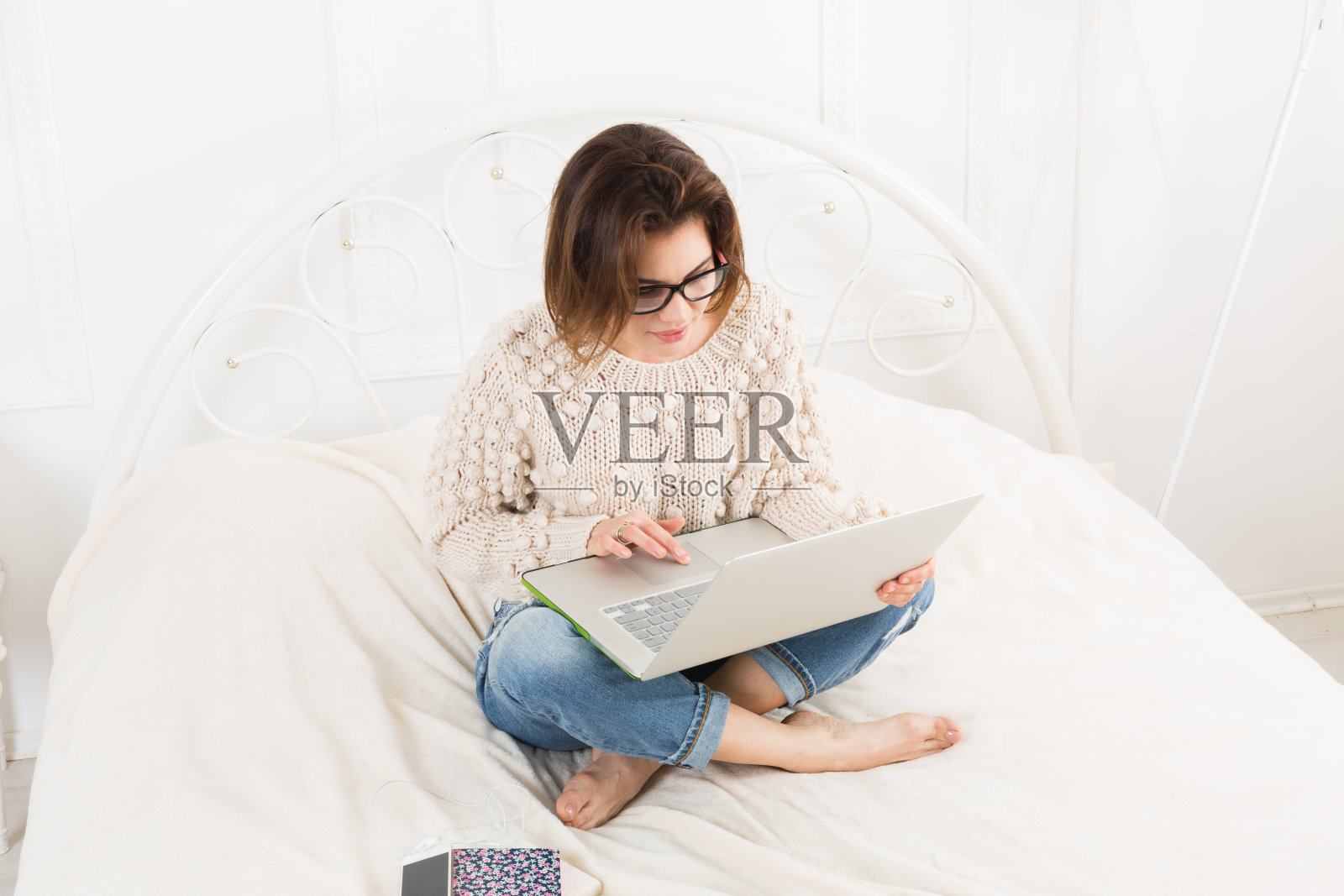 年轻女子在床上用笔记本电脑看书，很高调照片摄影图片