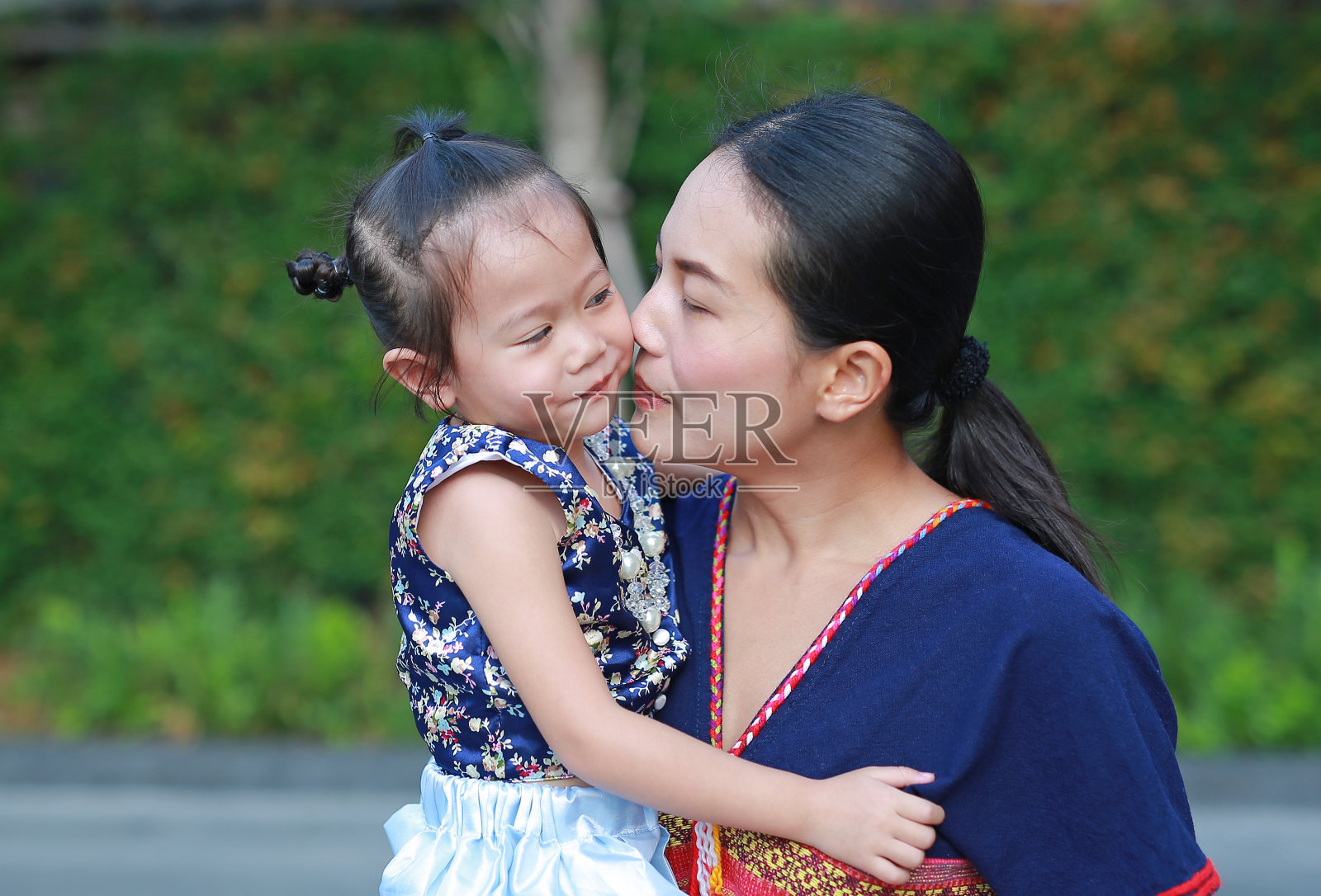 母亲和女儿在传统的宋干节服装亲吻的肖像。照片摄影图片
