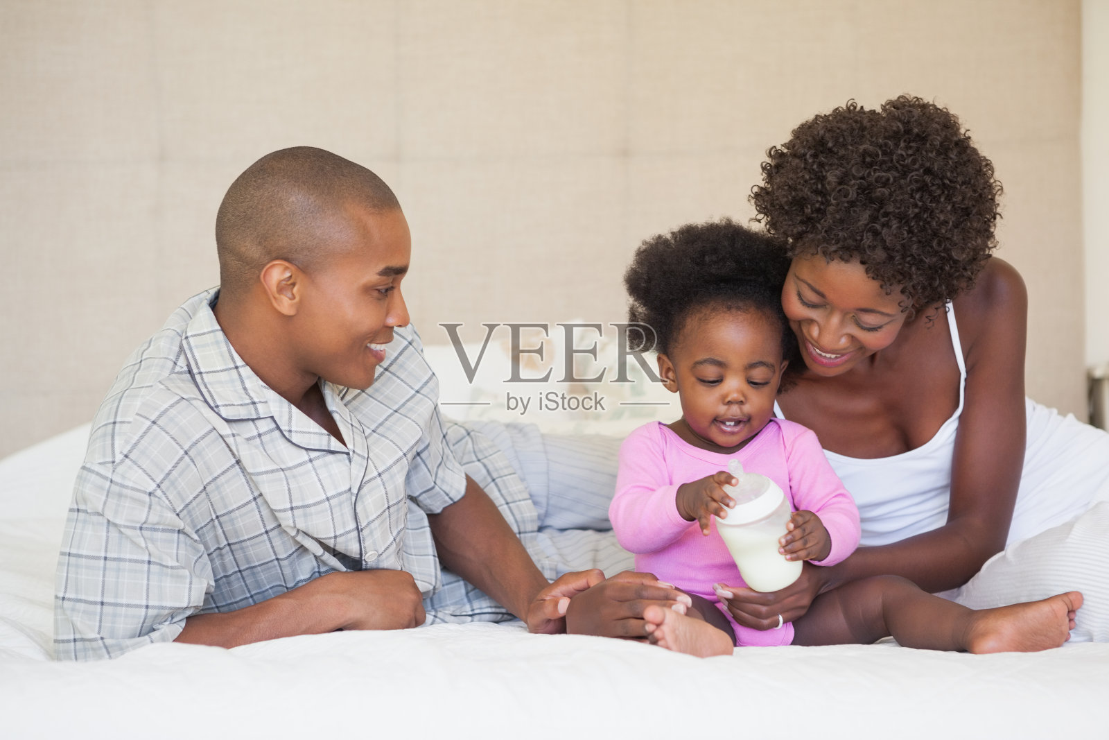 幸福的父母和女婴一起坐在床上照片摄影图片