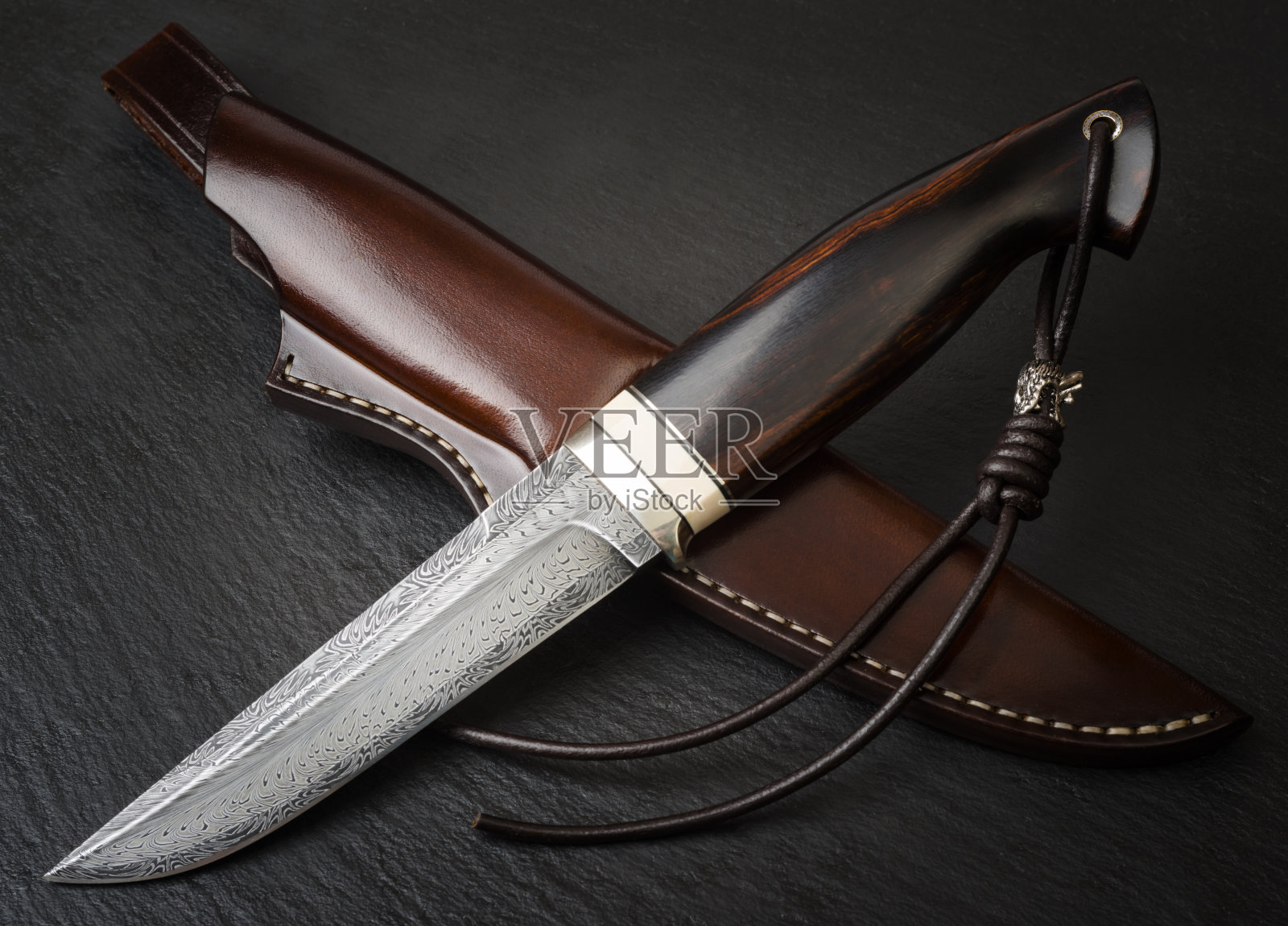 黑色背景上带有猛犸象牙的大马士革马赛克猎刀及手工皮革刀鞘照片摄影图片