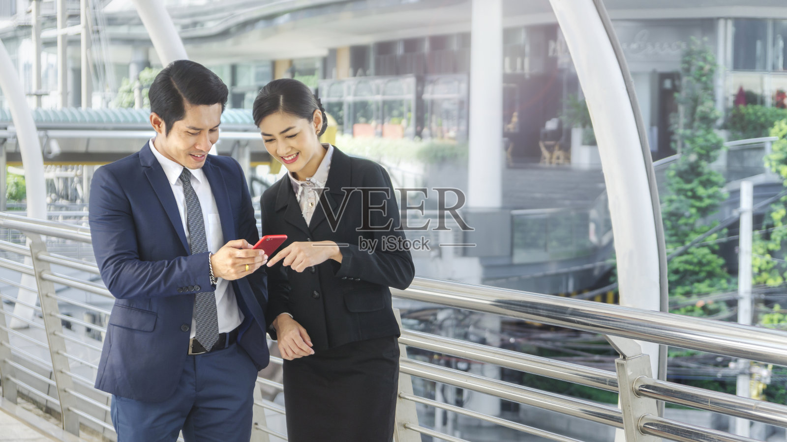 商务人士的团队，聪明的男人和女人交谈和使用智能手机在良好的感觉在室外步行方式的城市空间现代建筑照片摄影图片