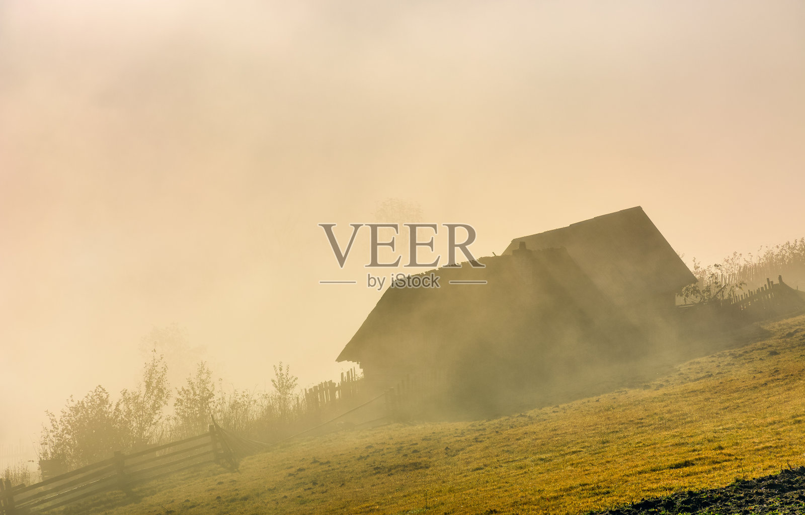 日出时雾气弥漫的山坡上的废弃谷仓照片摄影图片