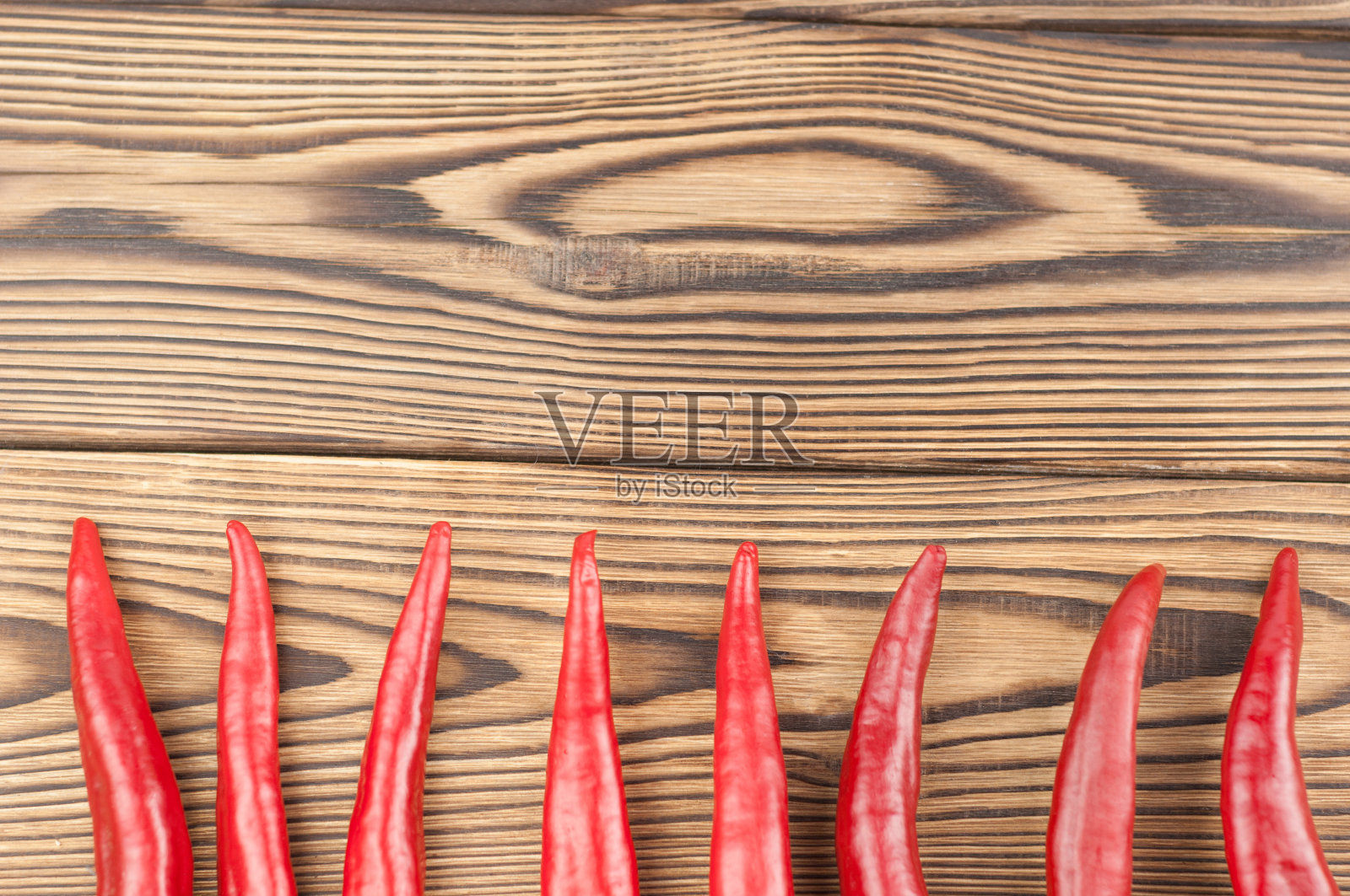 整排的红辣椒，新鲜的，成熟的，放在旧的棕色木块上照片摄影图片