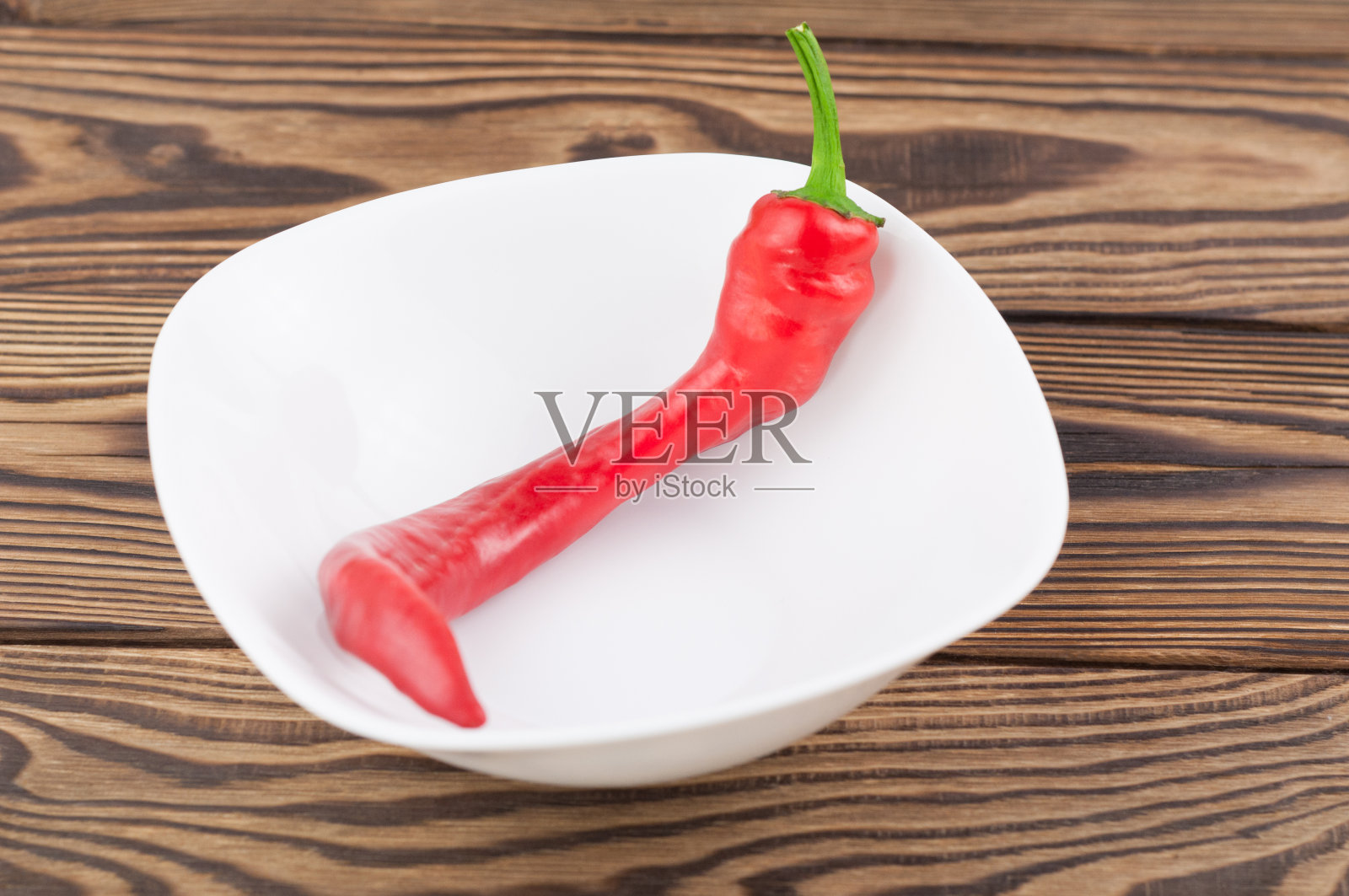 红色的完整的新鲜成熟的辣椒在白色陶瓷碗上的旧棕色木乡村板照片摄影图片