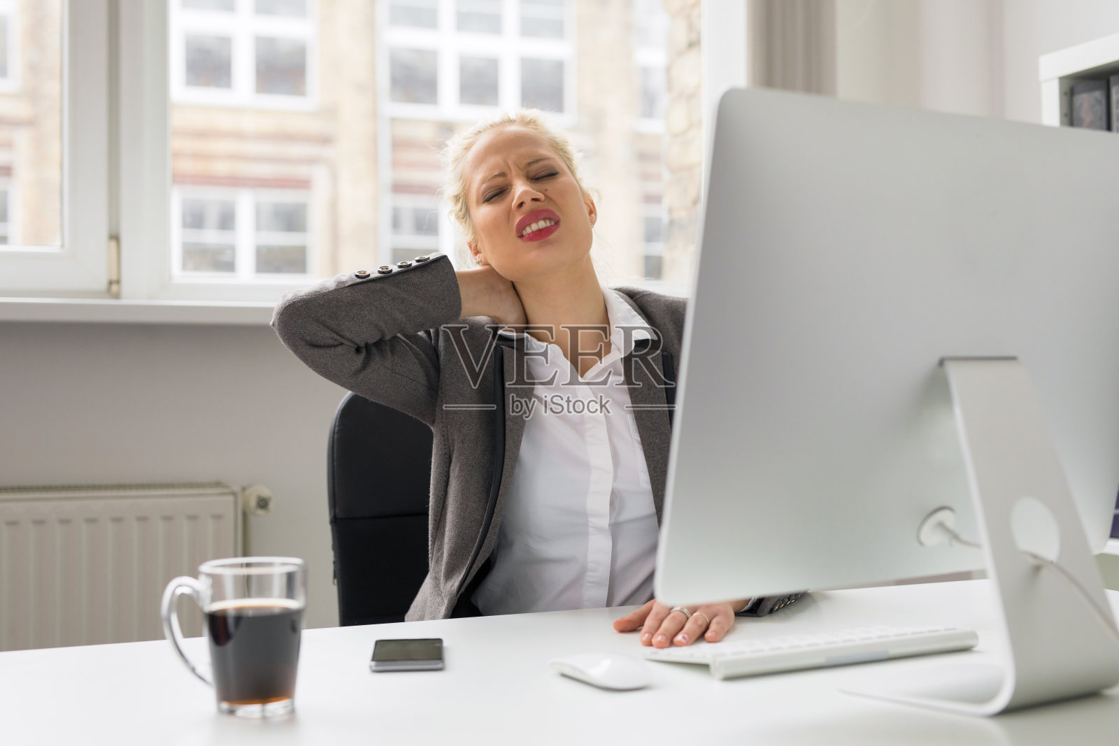 一个女人在办公室里痛苦地扼住脖子照片摄影图片