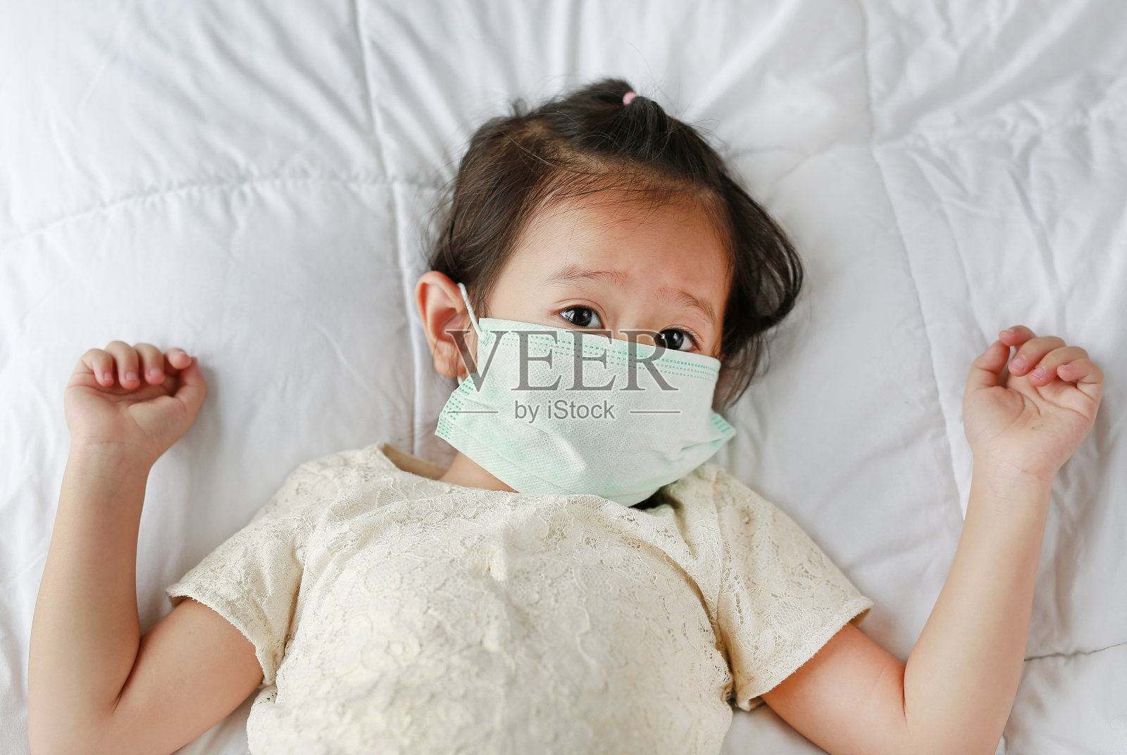 小女孩戴着防护面具躺在床上。照片摄影图片