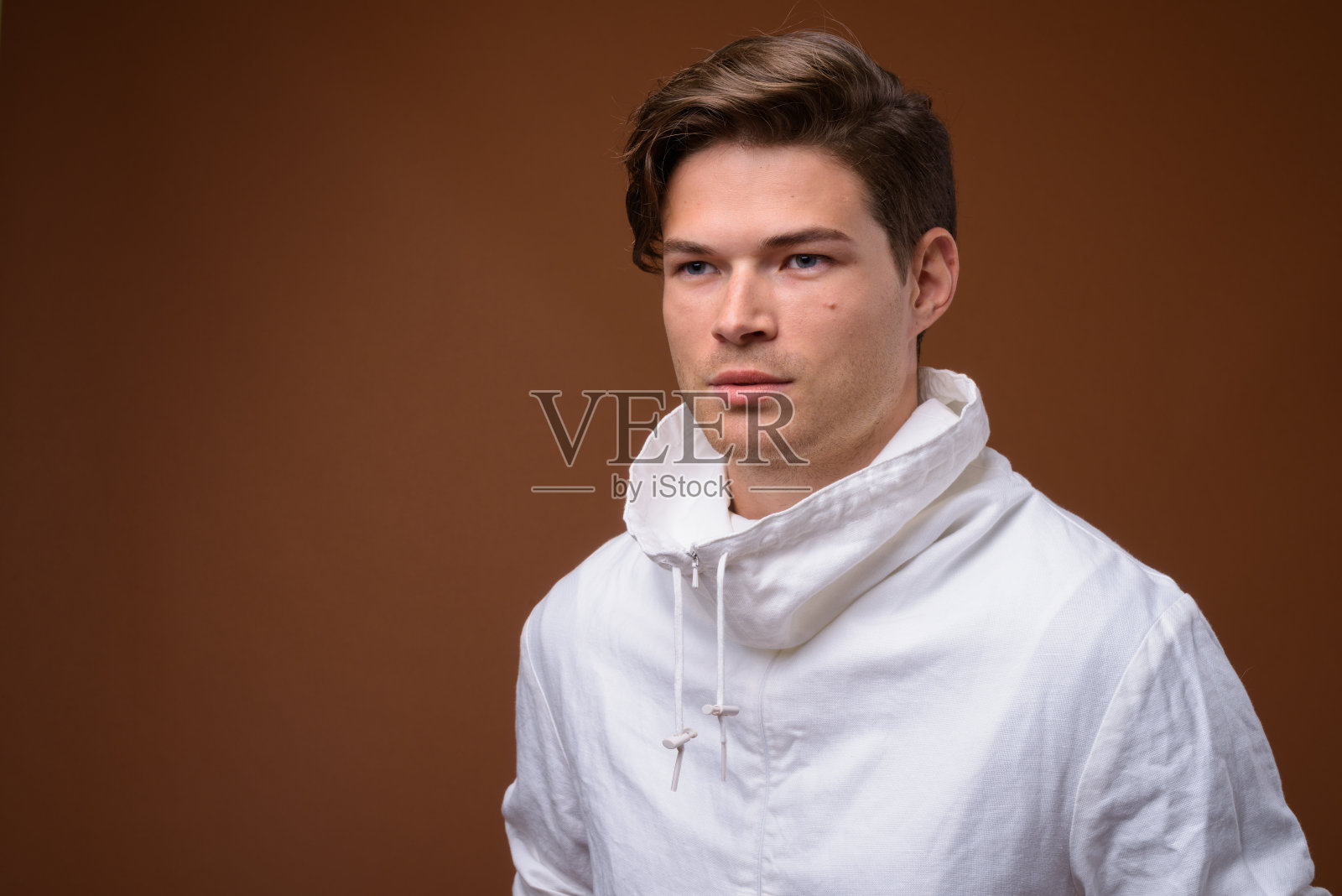 工作室拍摄的年轻英俊的男子穿着高领白色夹克，以彩色背景照片摄影图片