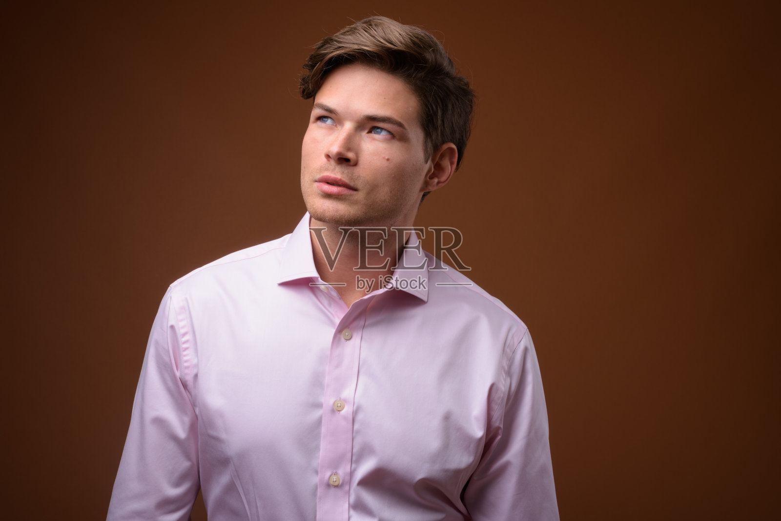 工作室拍摄的年轻英俊的商人穿着粉红色的衬衫，以彩色的背景照片摄影图片