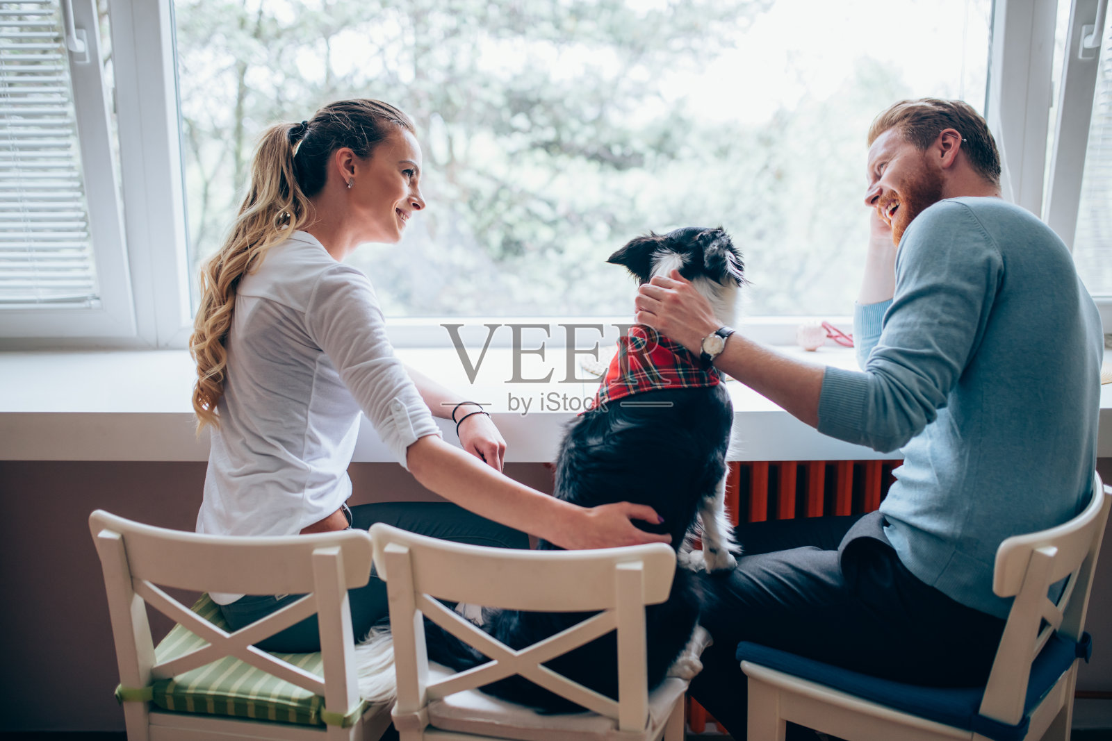 一对美丽的夫妇在家里放松，爱护他们的狗照片摄影图片