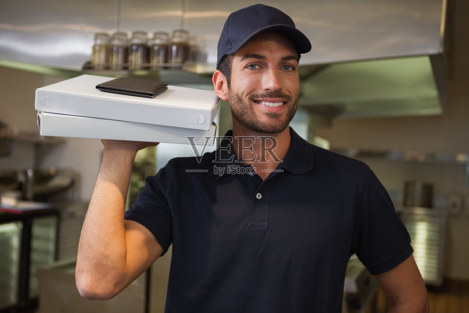 微笑的披萨送餐员拿着两个披萨盒子照片摄影图片