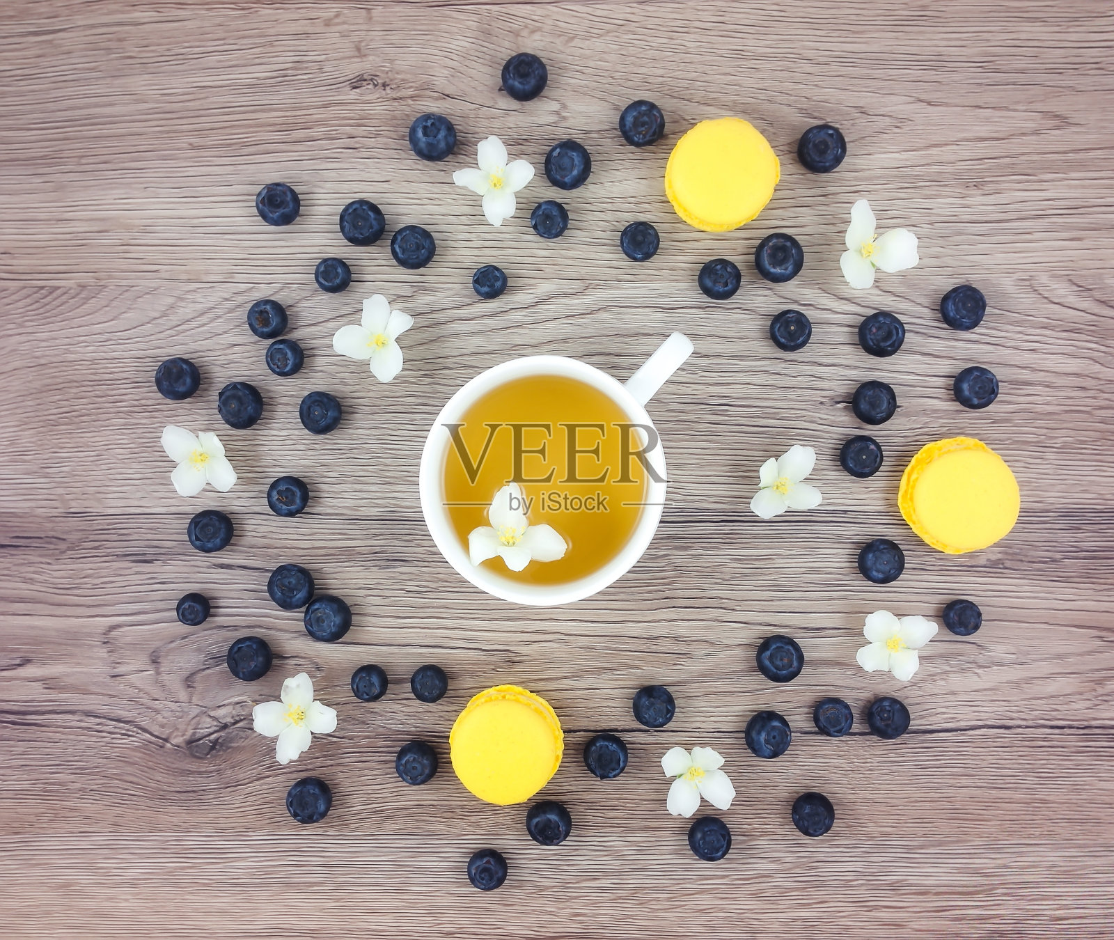 一杯热绿茶，鲜花和浆果放在木桌上。平躺照片摄影图片