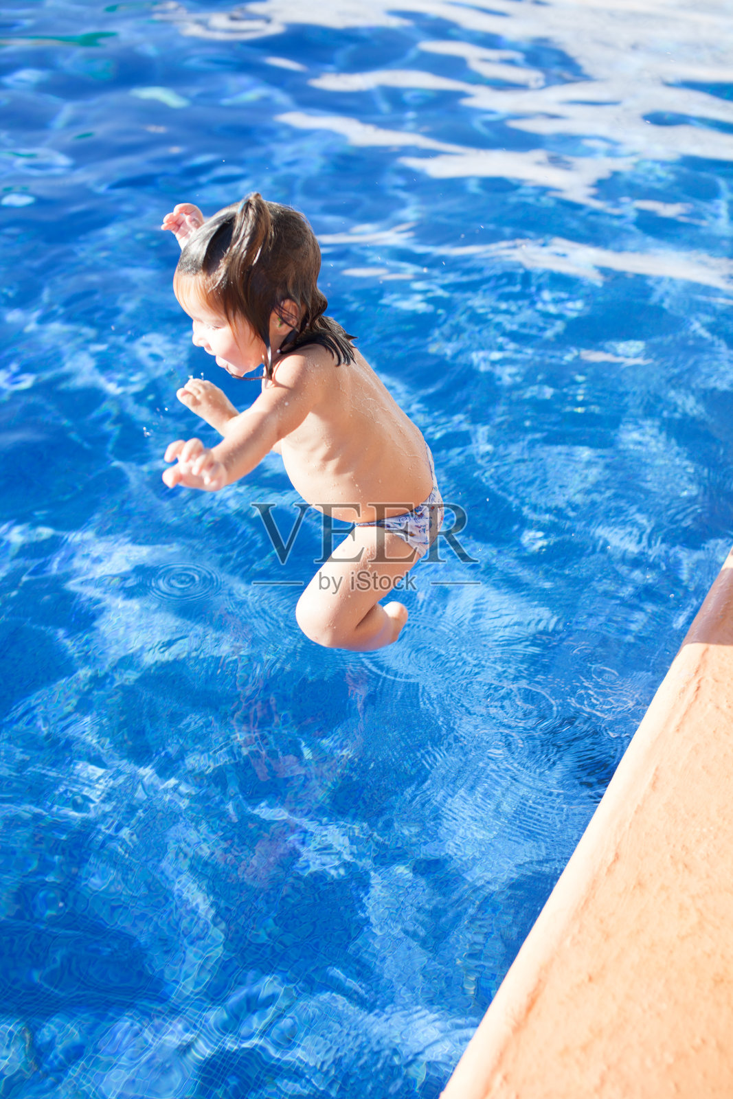 快乐的女孩在游泳池里跳照片摄影图片