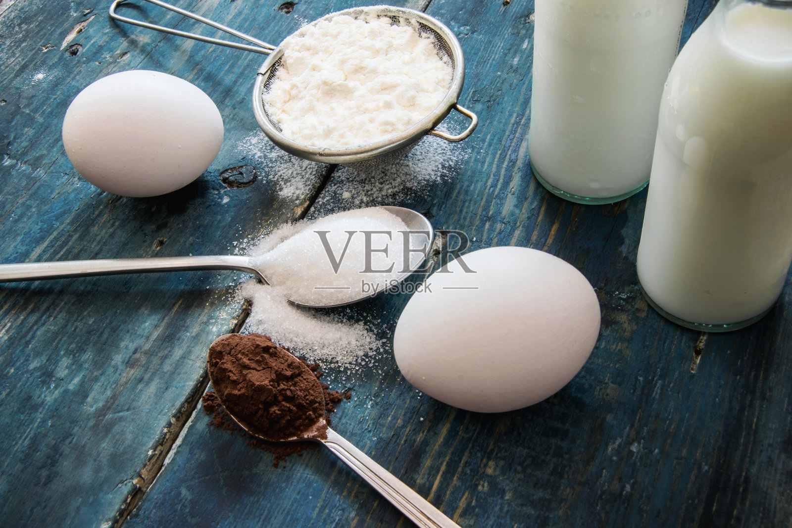 蛋糕真正的原料——鸡蛋，牛奶，面粉和可可放在蓝色的乡村桌子上照片摄影图片