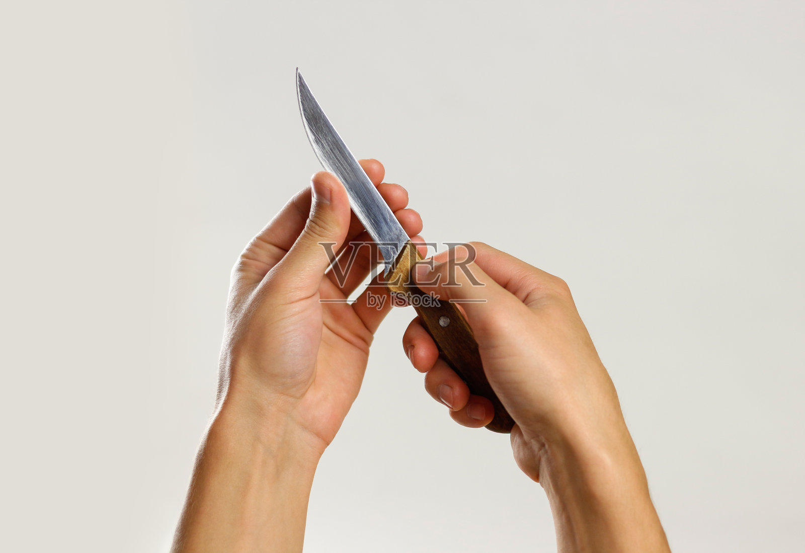 男性的手握着一把锋利的木柄菜刀。孤立在灰色背景。特写镜头照片摄影图片