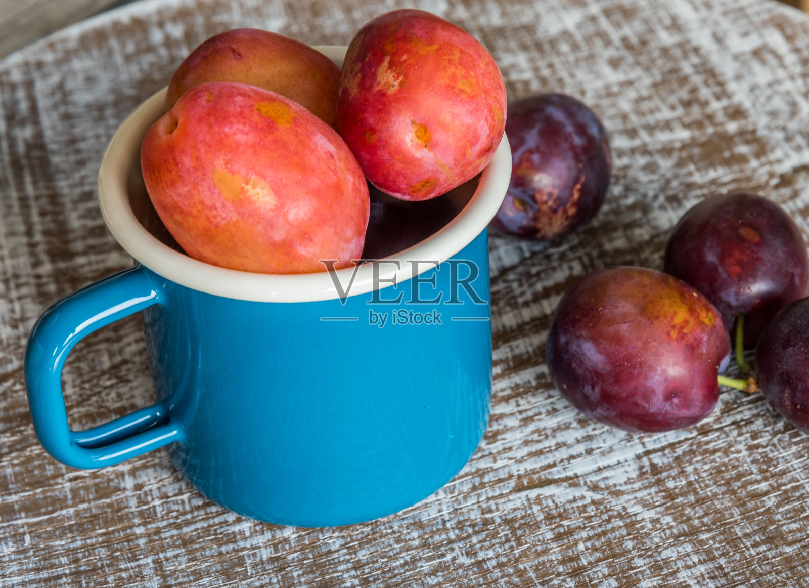 蓝色杯子里的新鲜李子照片摄影图片