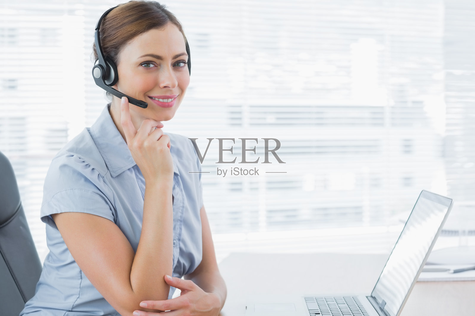 电话中心职员戴着耳机坐在办公桌前照片摄影图片