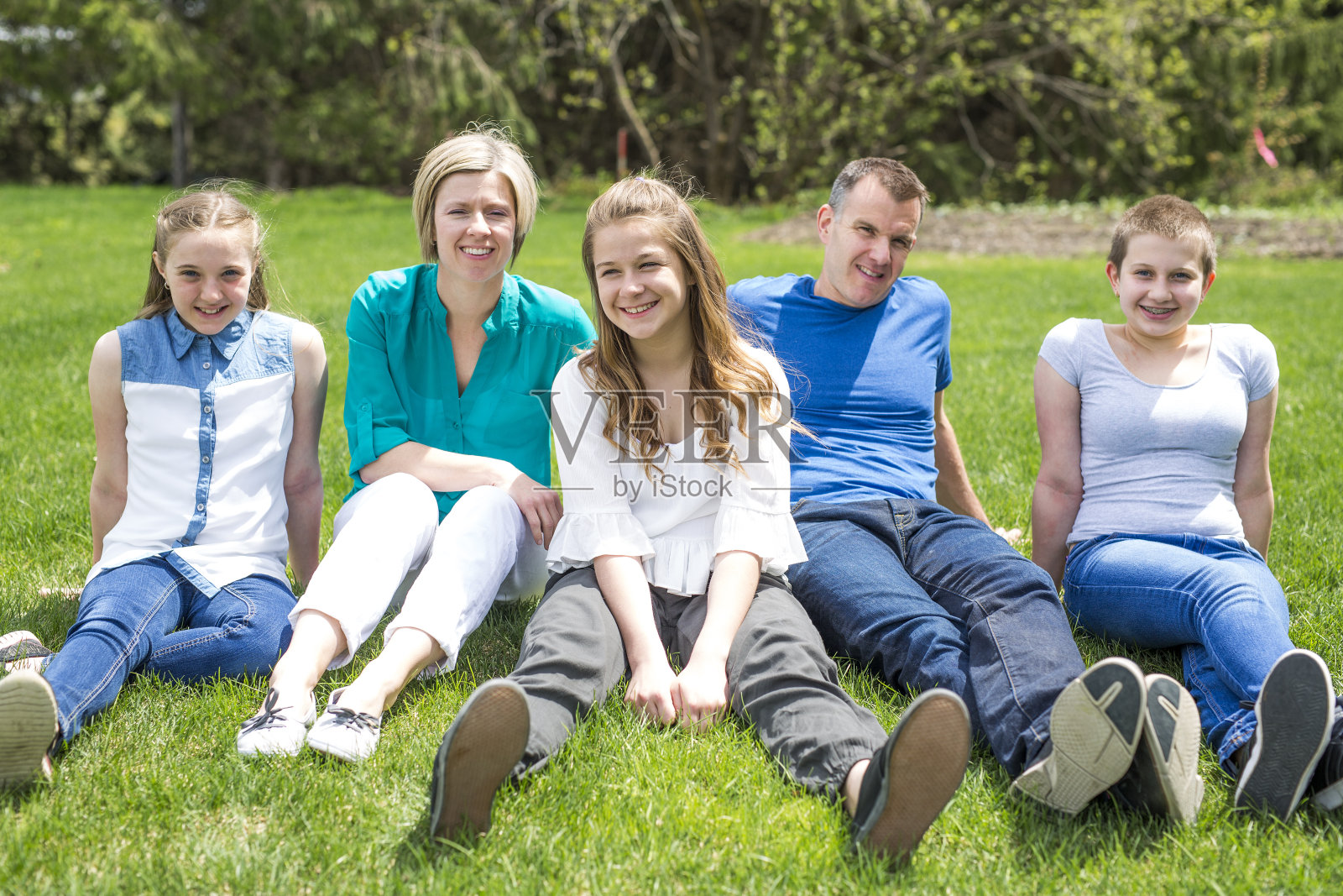 快乐的家庭成员坐在绿色的草地外面照片摄影图片