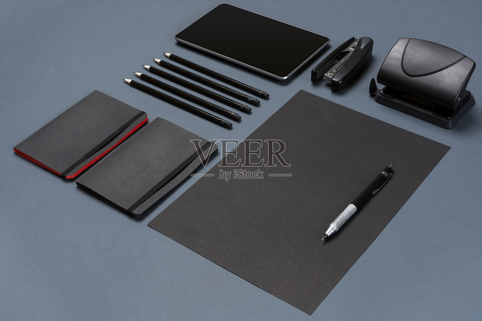 一套黑色的办公文具放在灰色的背景上，平铺着照片摄影图片