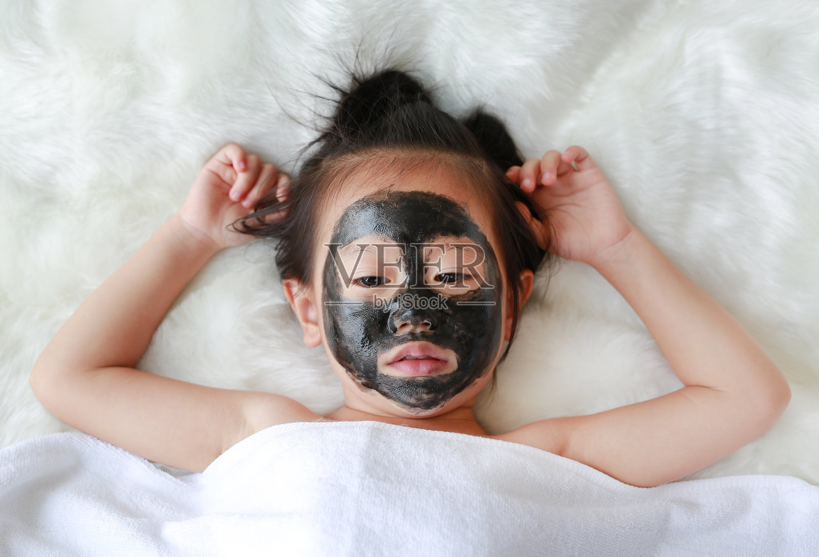 小女孩在煤剥皮面膜，美的概念。照片摄影图片